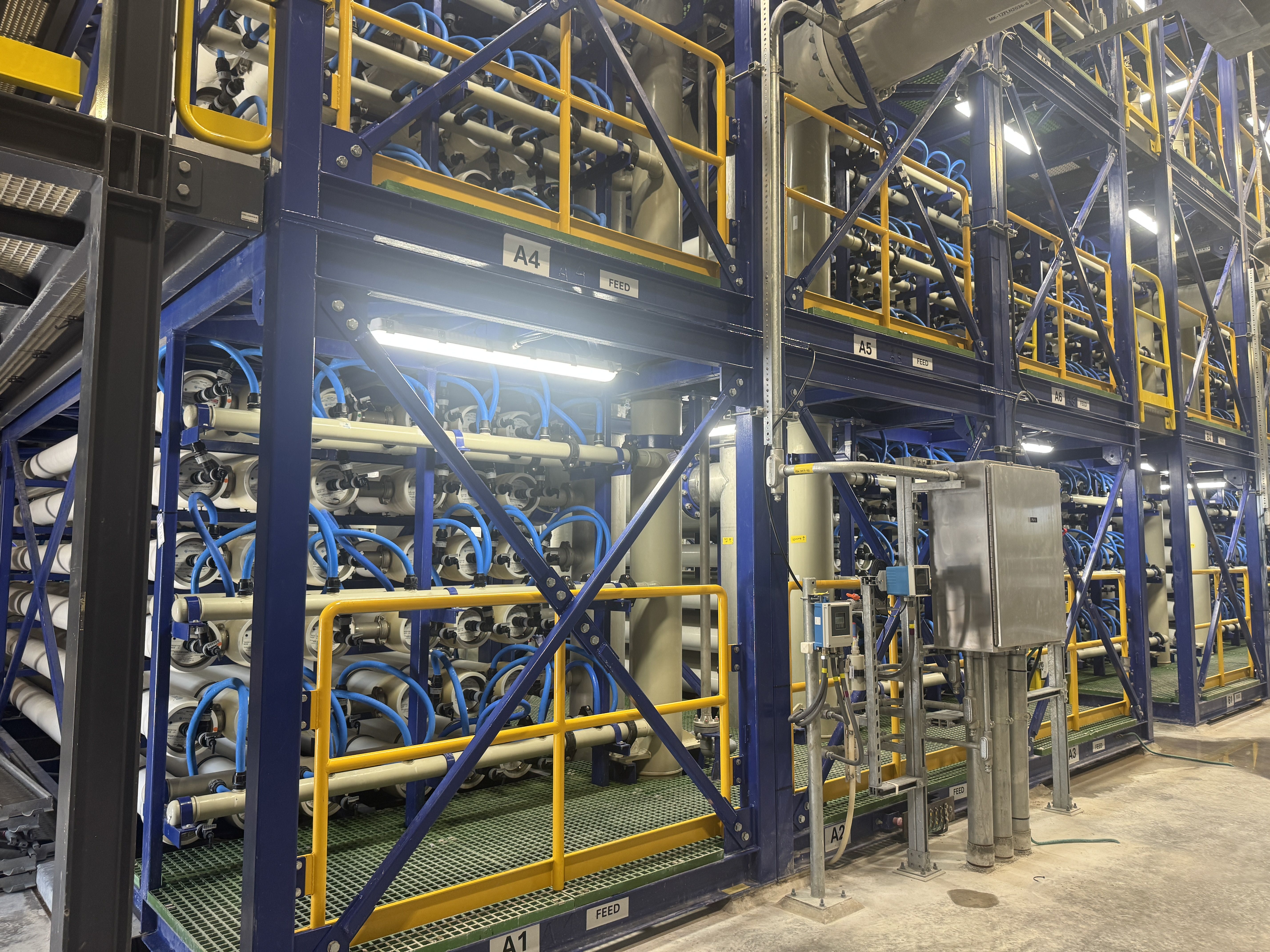Water filtration systems behind bellow and yellow steel frames inside the water treatment facility