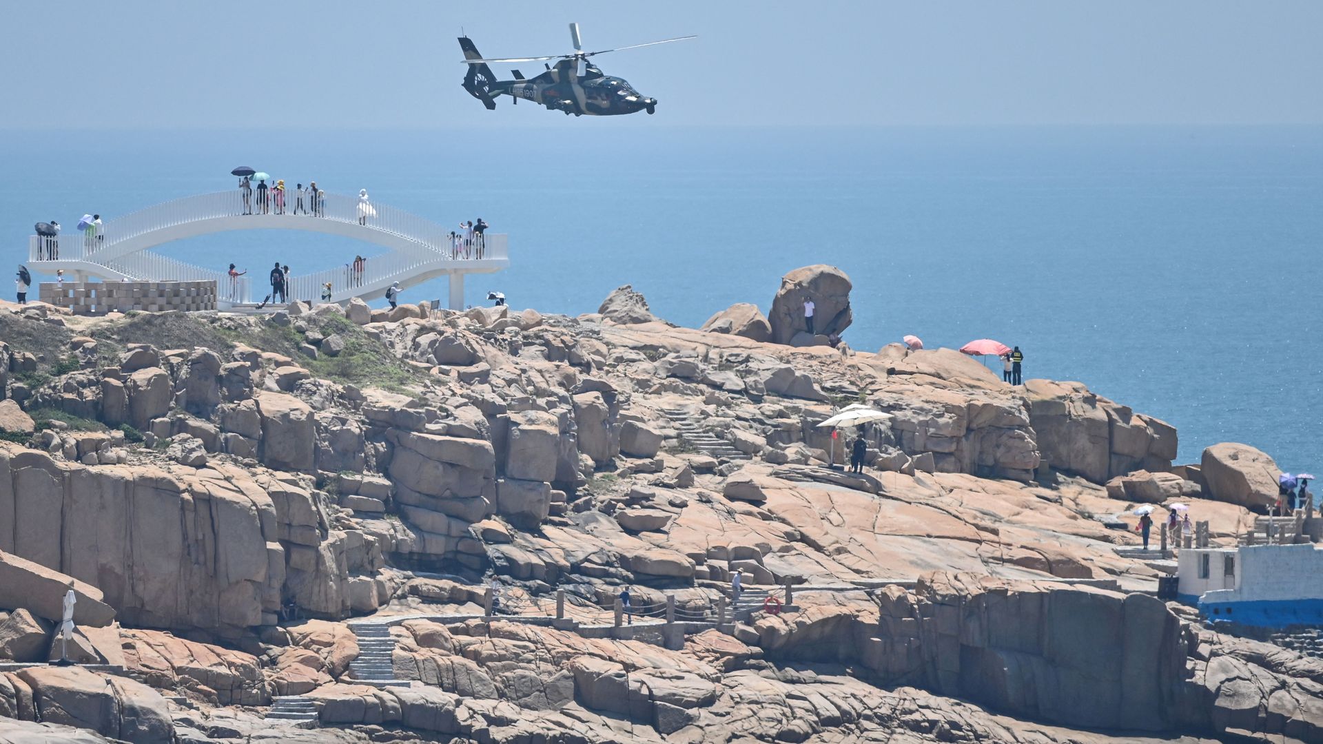 Tourists look on as a Chinese military helicopter flies past Pingtan island, one of mainland China's closest point from Taiwan, in Fujian province on August 4.