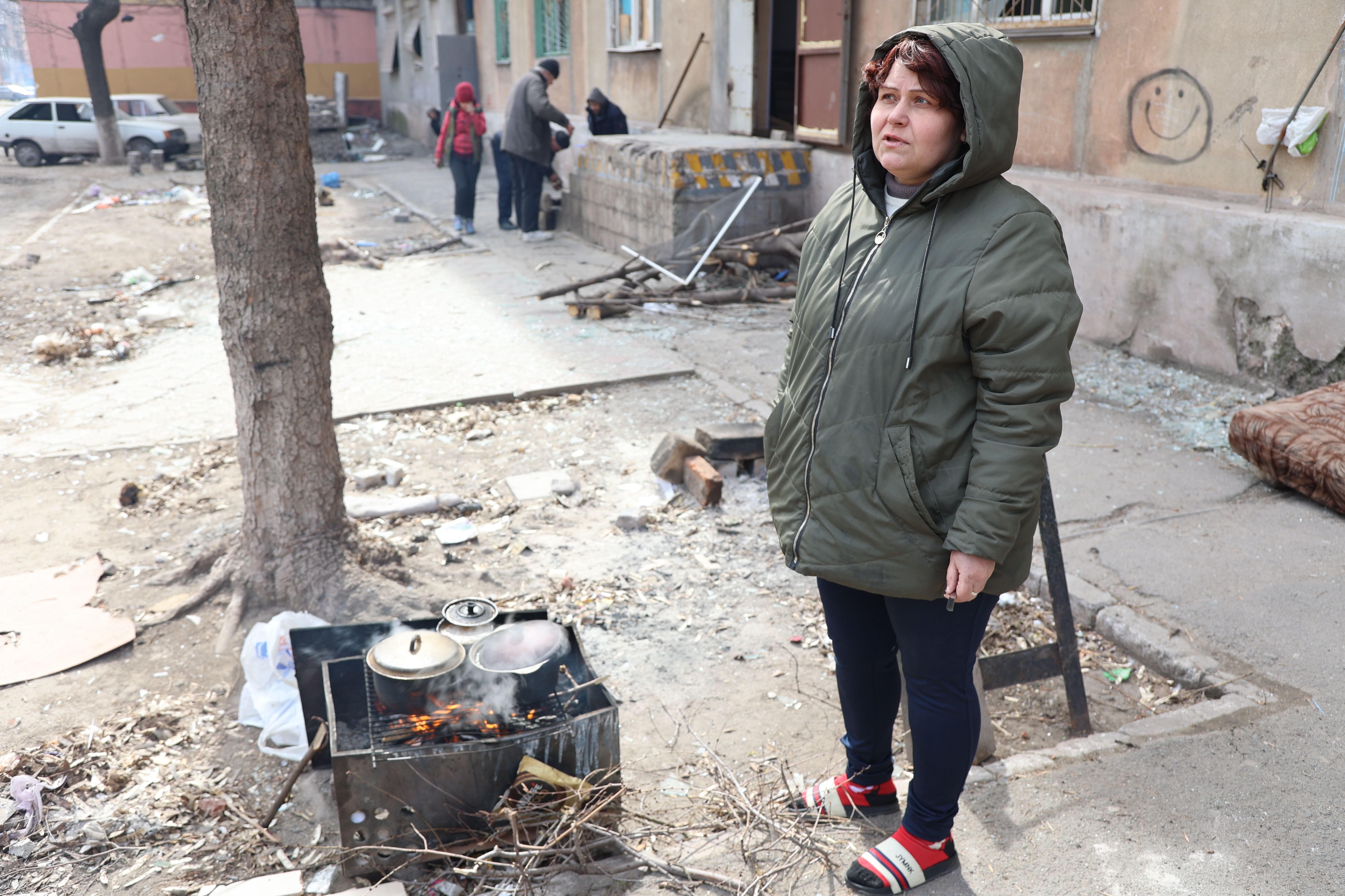 I civili cucinano il cibo tra le macerie di un condominio danneggiato dal bombardamento della città ucraina di Mariupol, militare russo e separatista filo-russo del 29 marzo.