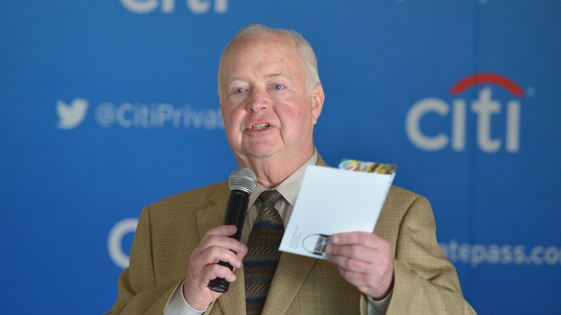 A man talks to an audience with a microphone in his hand. 