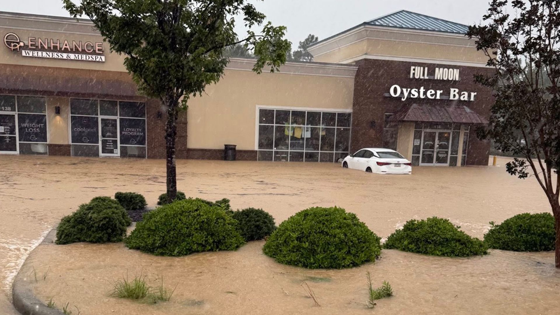 A Facebook photo showing floodwaters inundating the Full Moon Oyster Bar's carpark in the Town of Southern Pines, North Carolina, with floodwaters up to the wheels of a white car parked outside. 