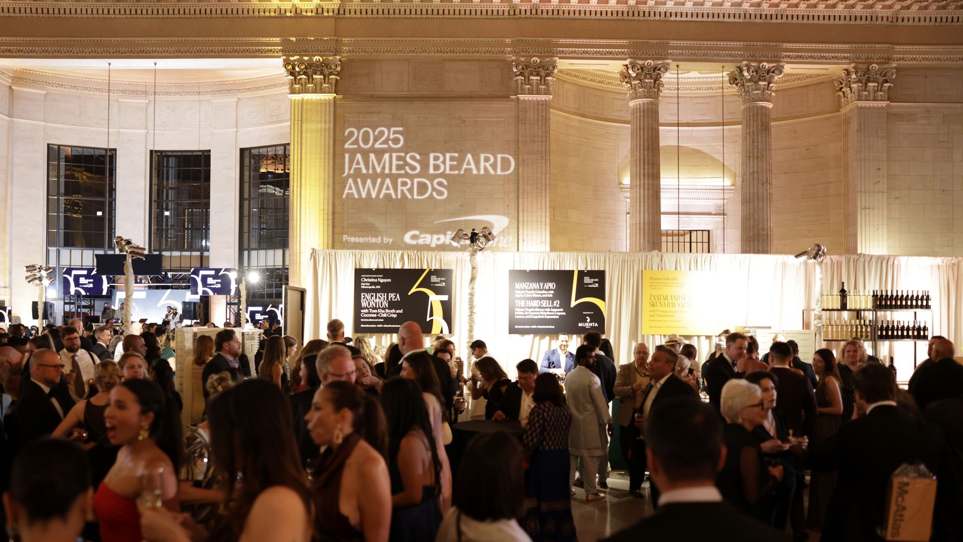 Grand, columned hall filled with guests in formal attire for the James Beard Awards.