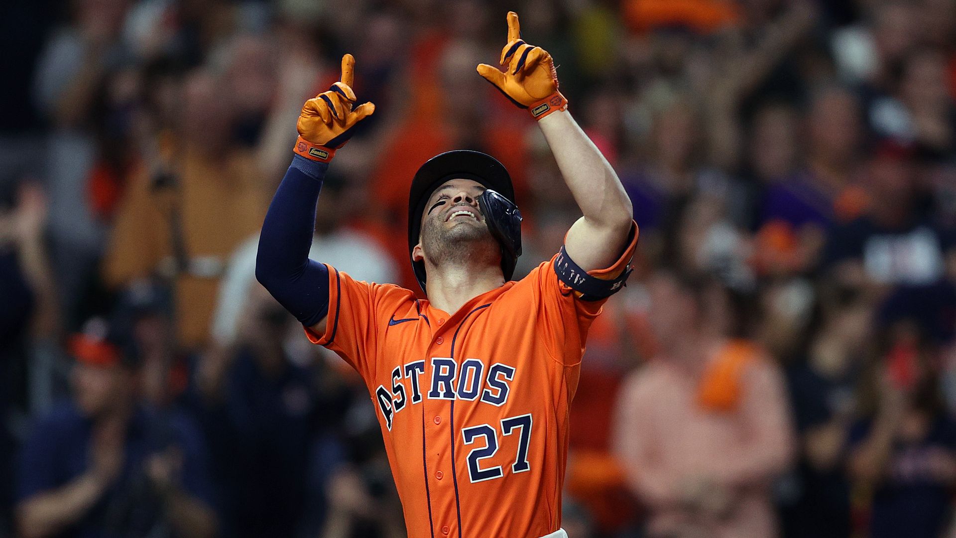 Houston's Jose Altuve wearing an orange jersey celebrates by pointing his fingers in the air. 