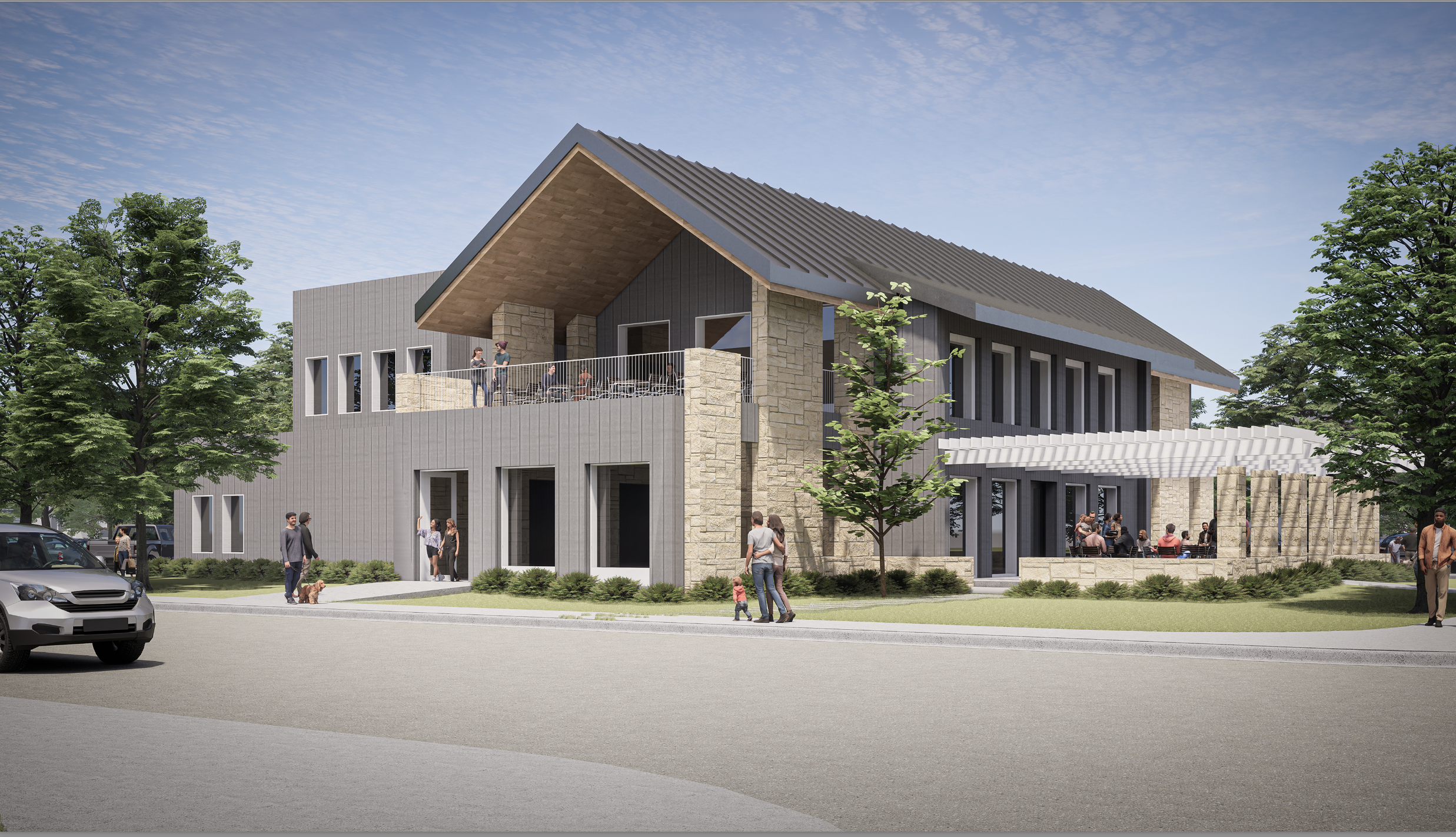 Modern two-story building with gray siding and stone accents, outdoor seating areas, people walking and socializing, green trees, and clear blue sky.