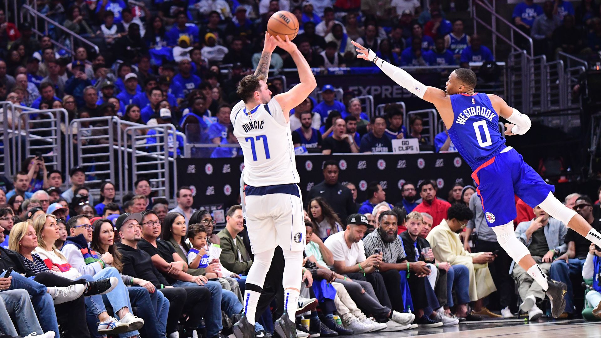 A photo of Luka Doncic trying to shoot a basketball while Russell Westbrook tries to stop him 