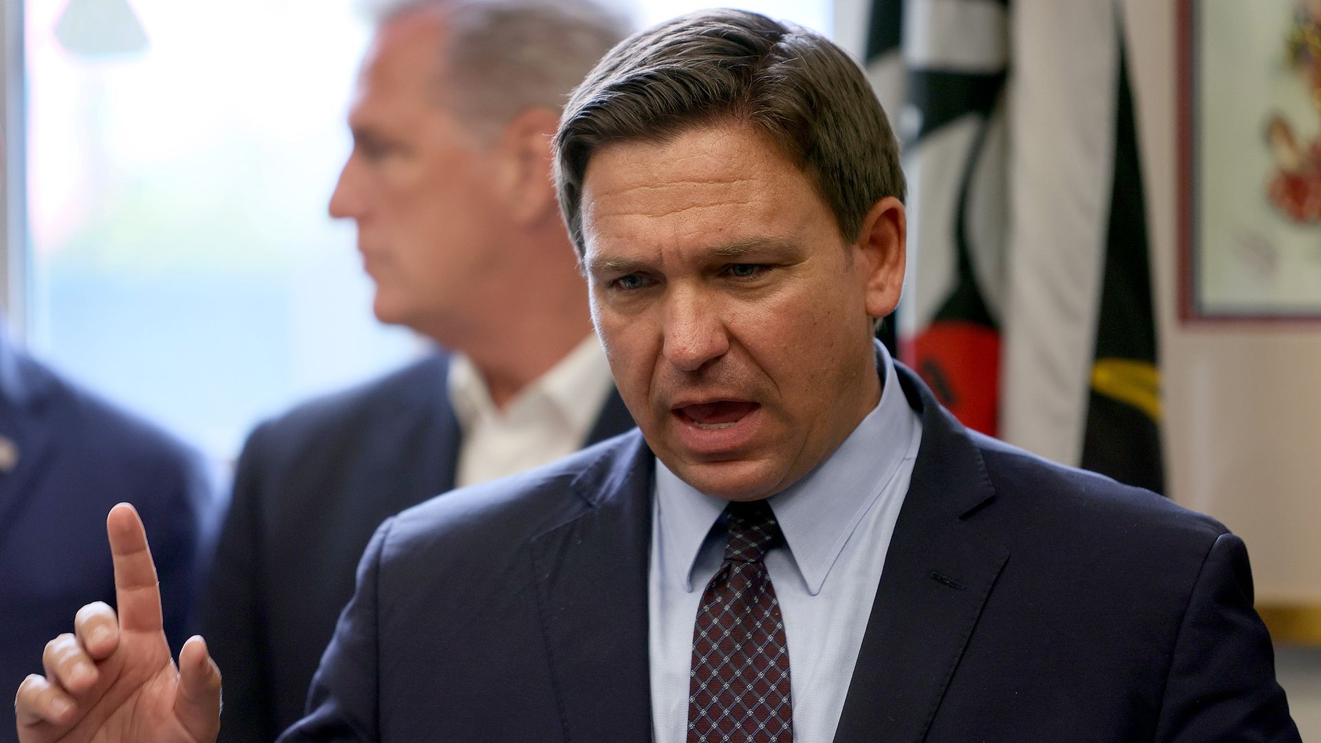 Photo of Ron DeSantis speaking into a mic while raising a finger in the air