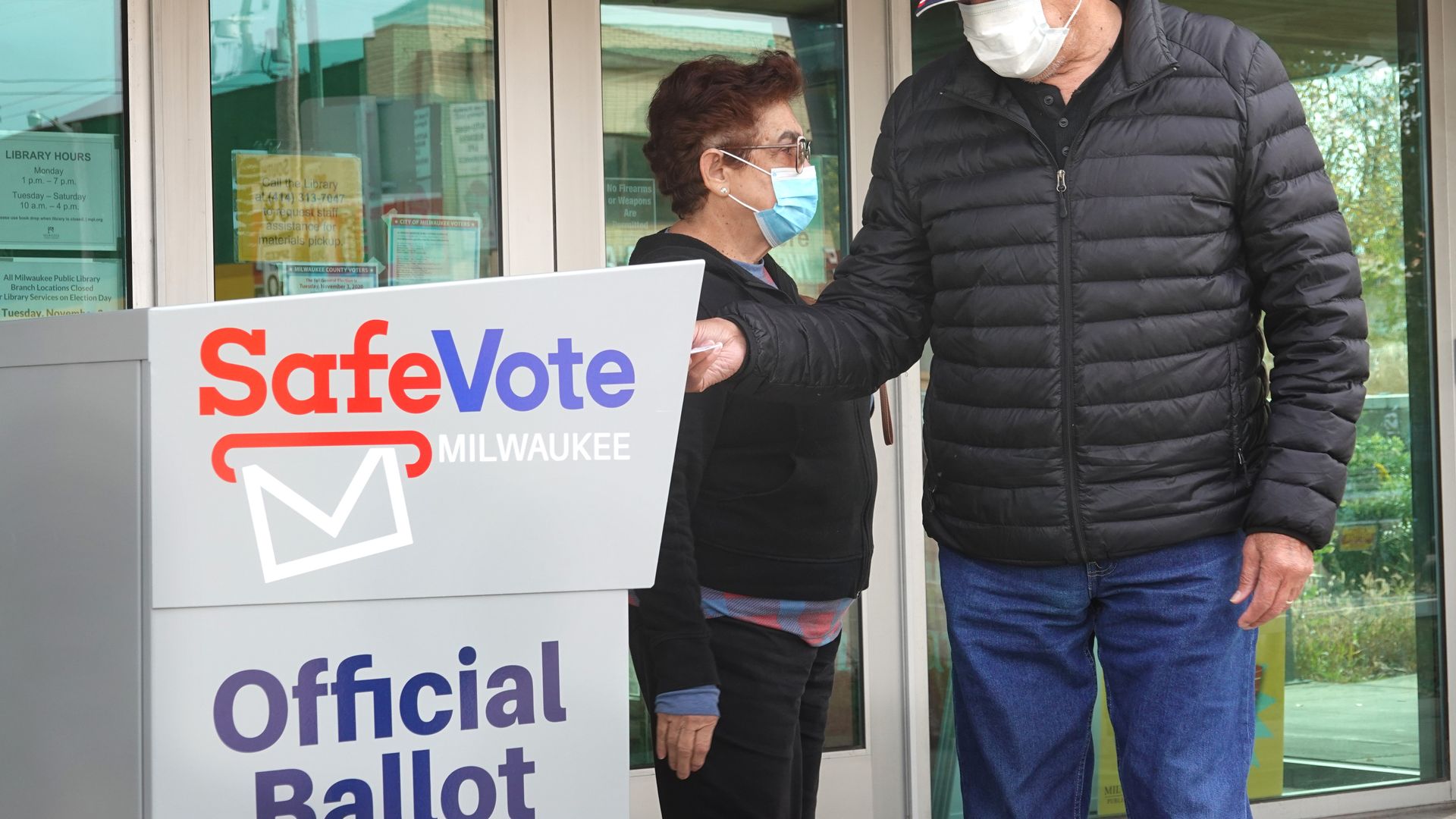 Picture of a man putting a ballot in a drop box