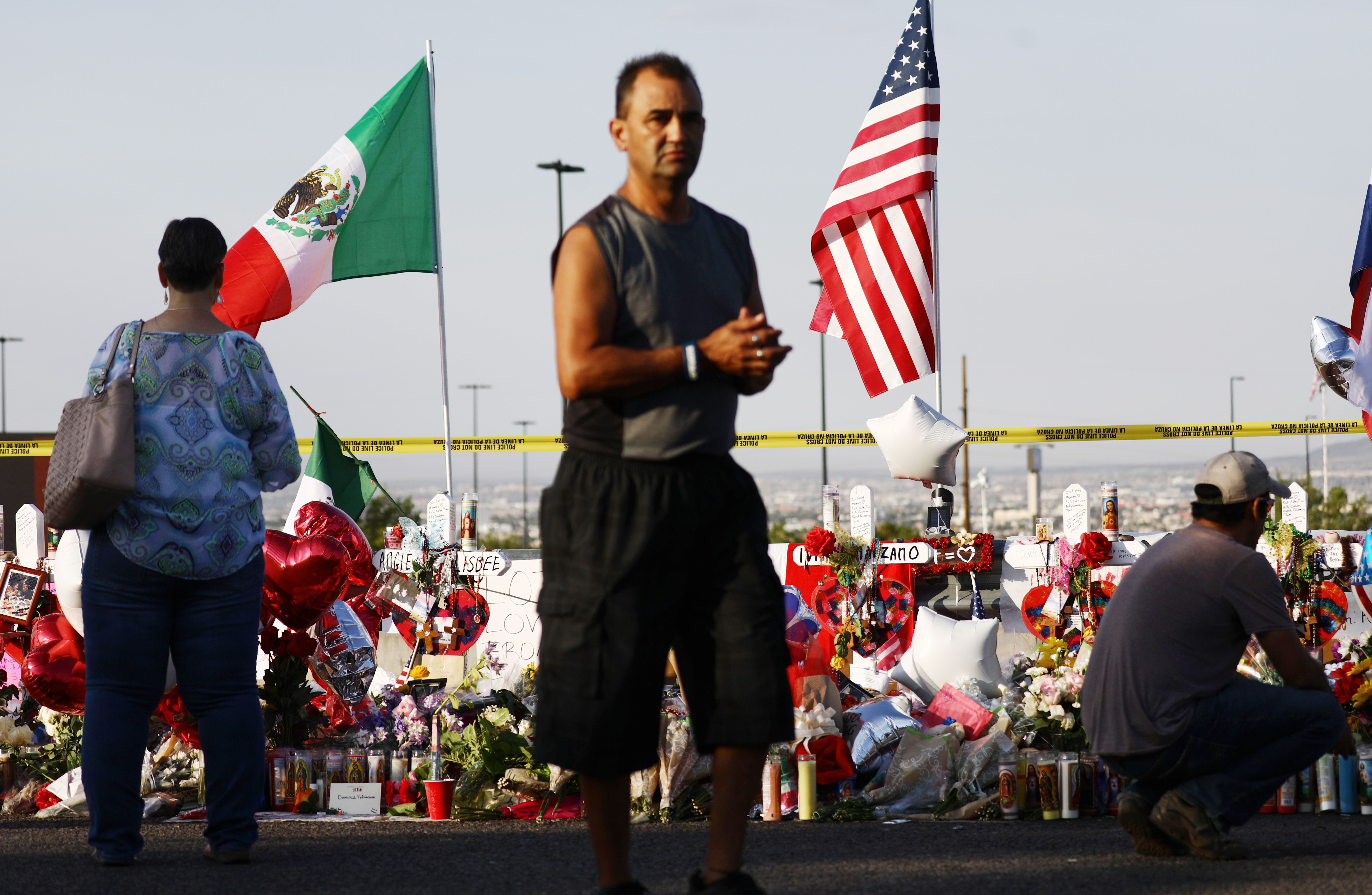 he Mexican and U.S. flags fly at a makeshift memorial honoring victims outside Walmart