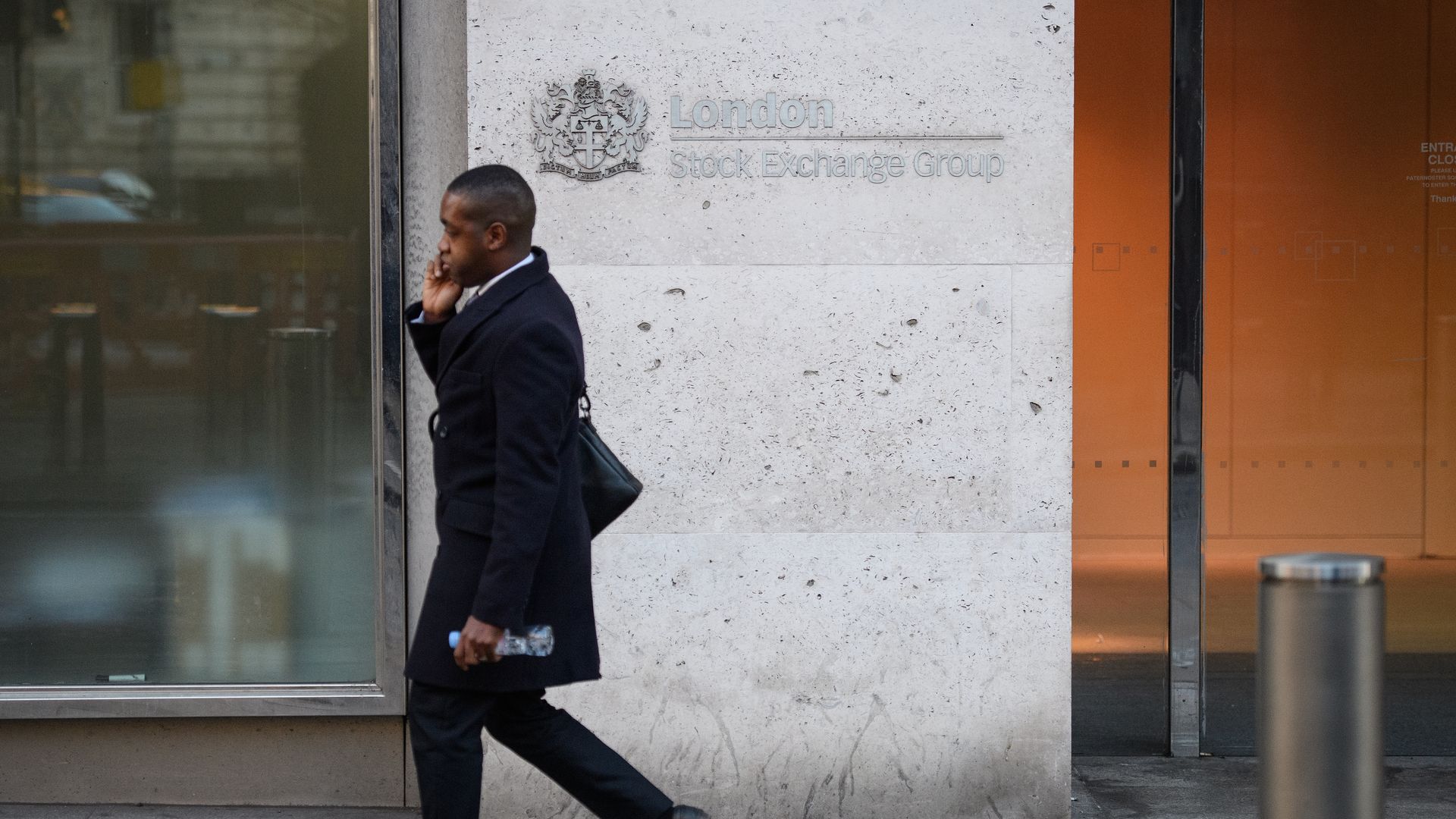 A man walking in front of the London Stock Exchange building