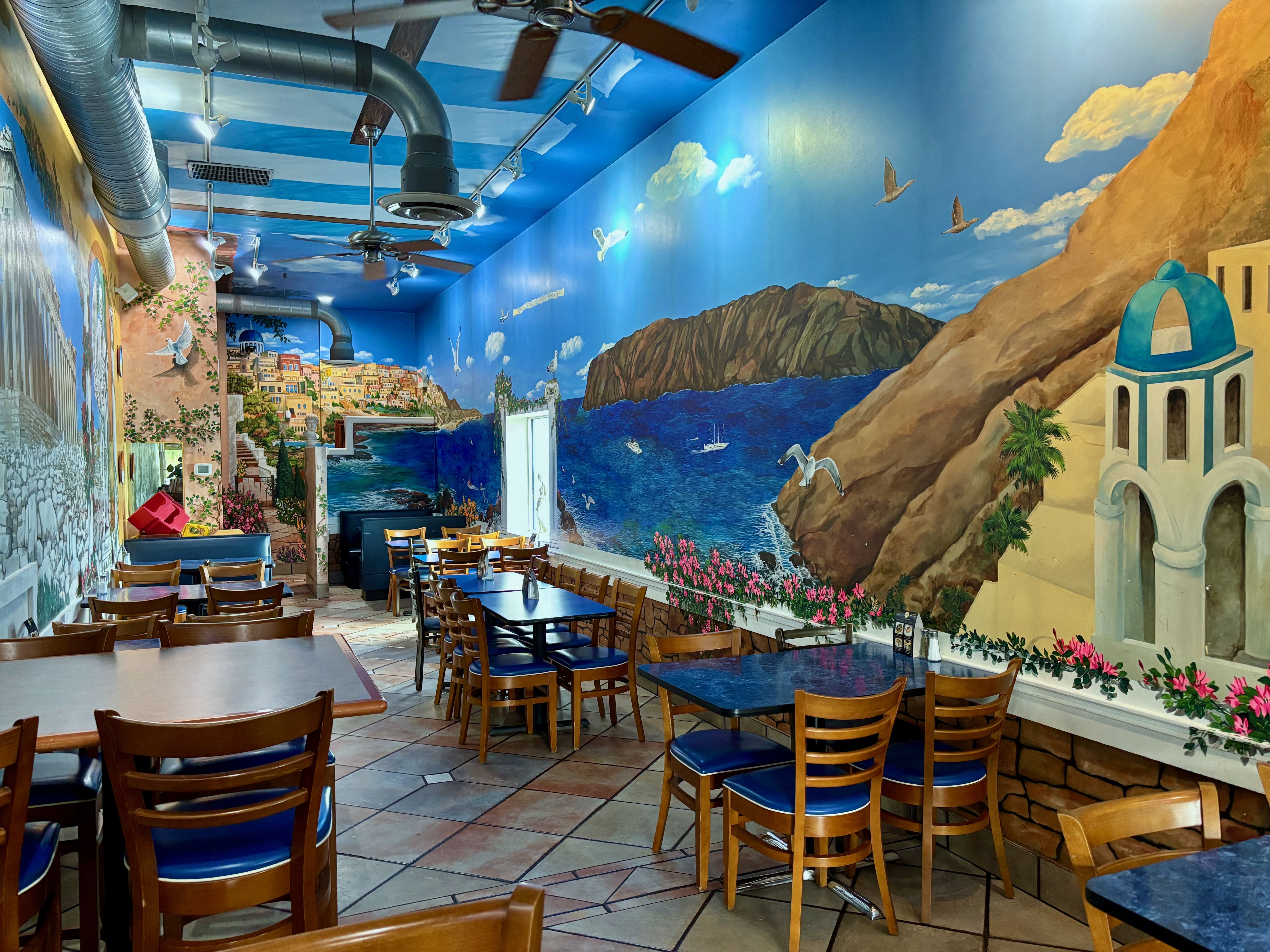 An overview of the dining area, with another mural depicting a Greecian coast