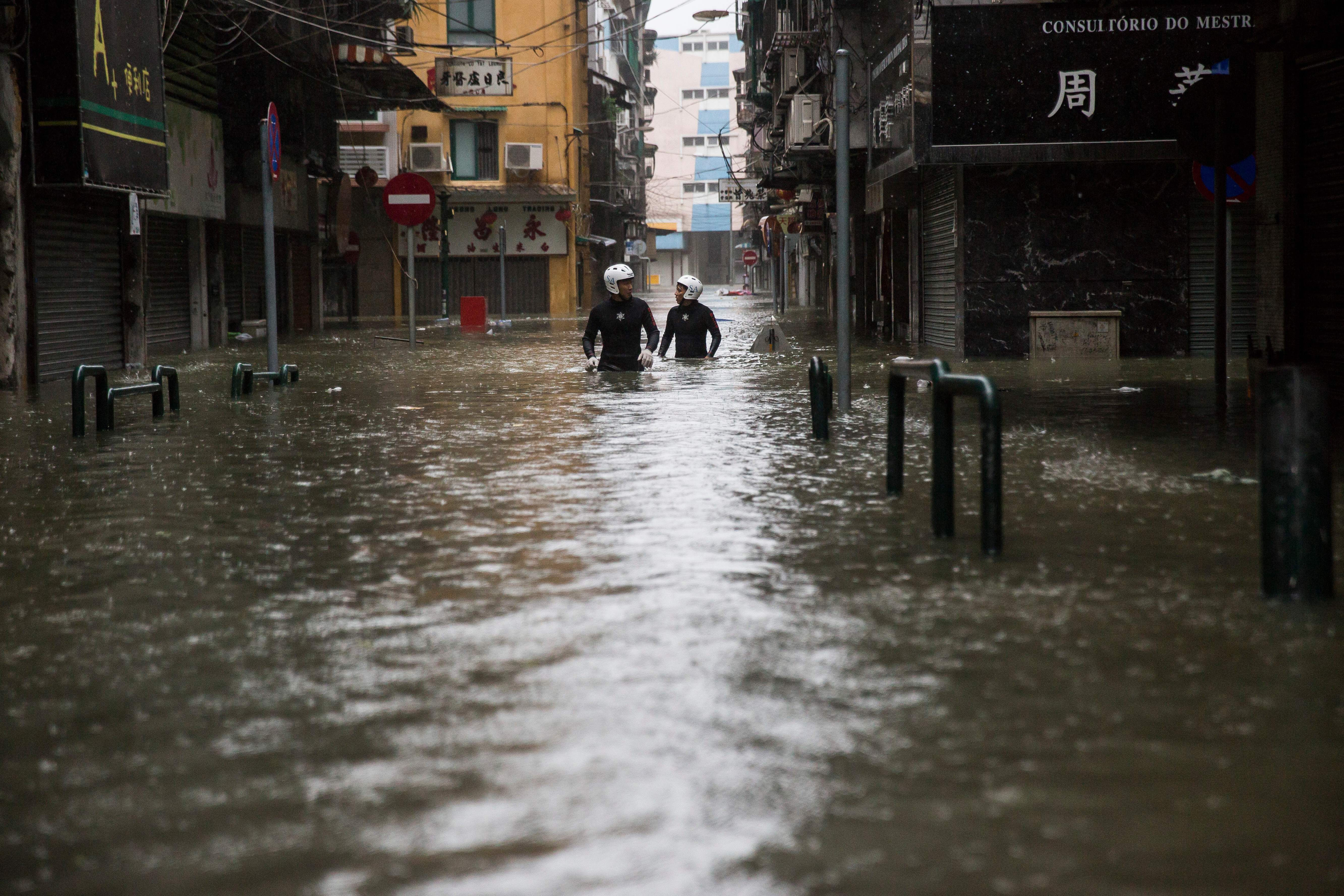 Residents walk through a flooded street in Macau