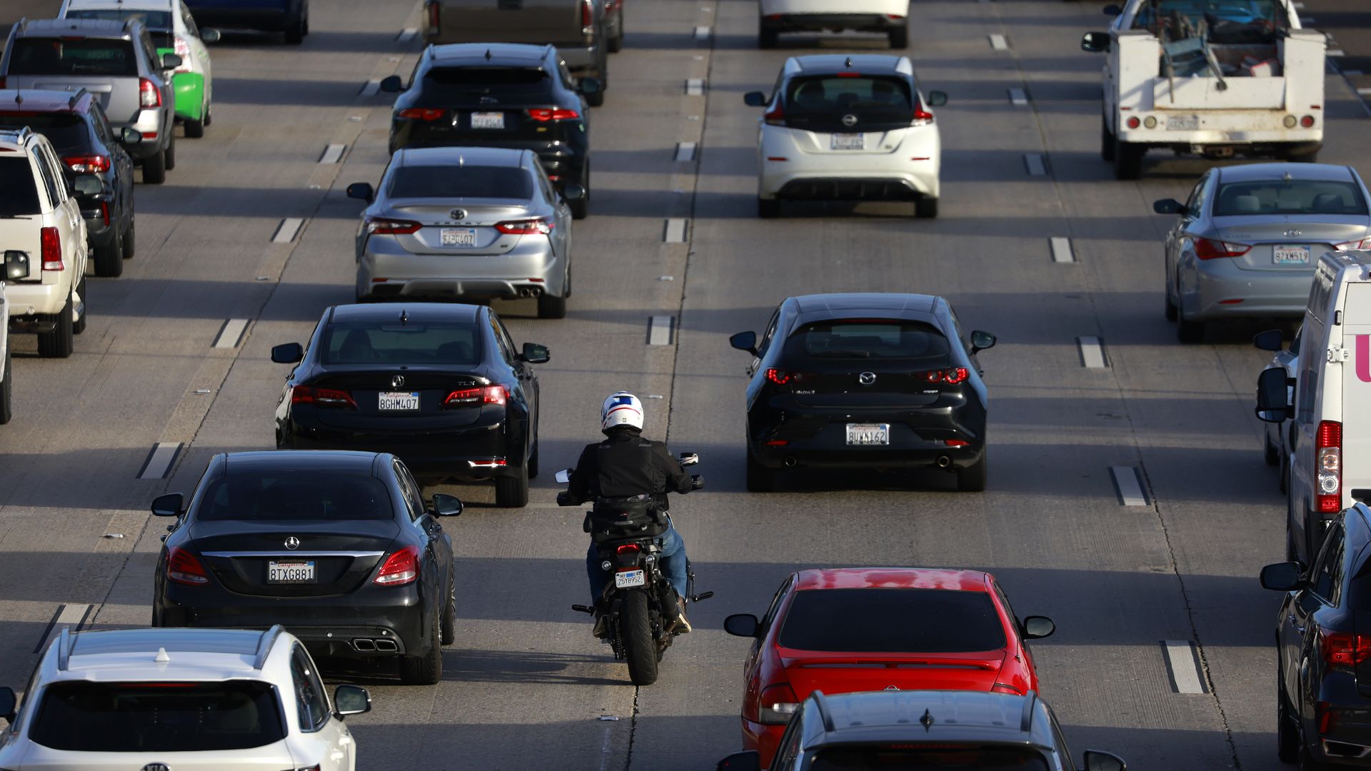 a motorcyclist splitting lanes by driving between freeway traffic