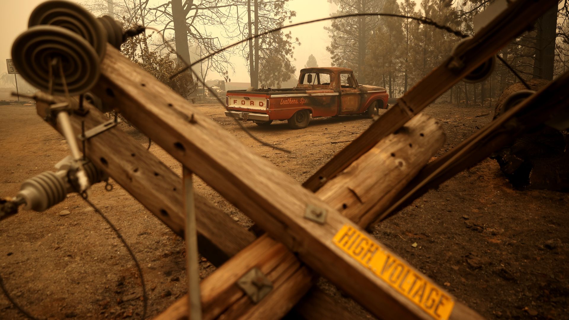A partially burned truck sits parked near a downed electrical power pole after the Dixie Fire moved through the area on August 11, 2021 in Greenville, California