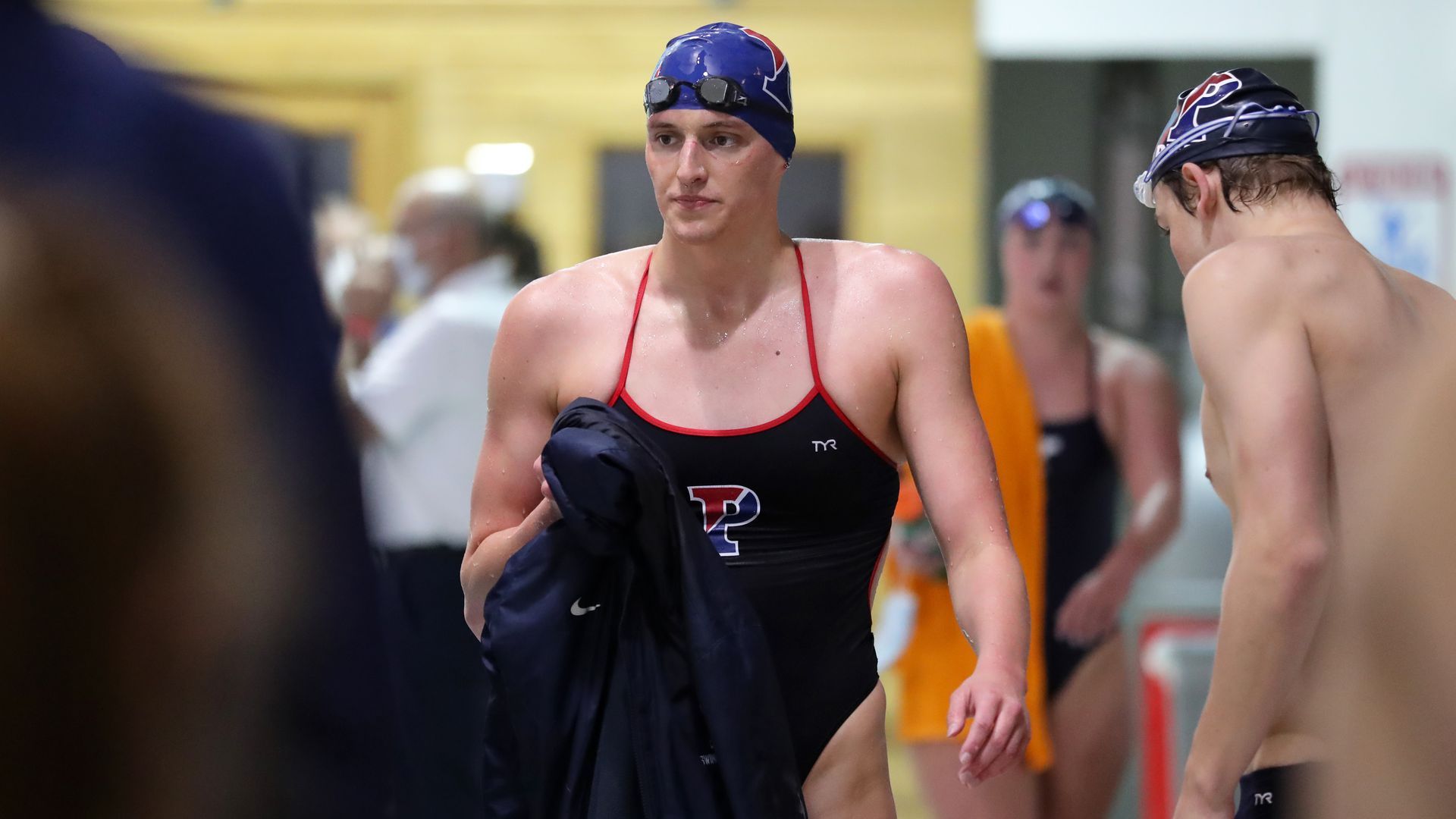 Picture of Lia Thomas wearing a one-piece swimsuit with a cap and holding a towel