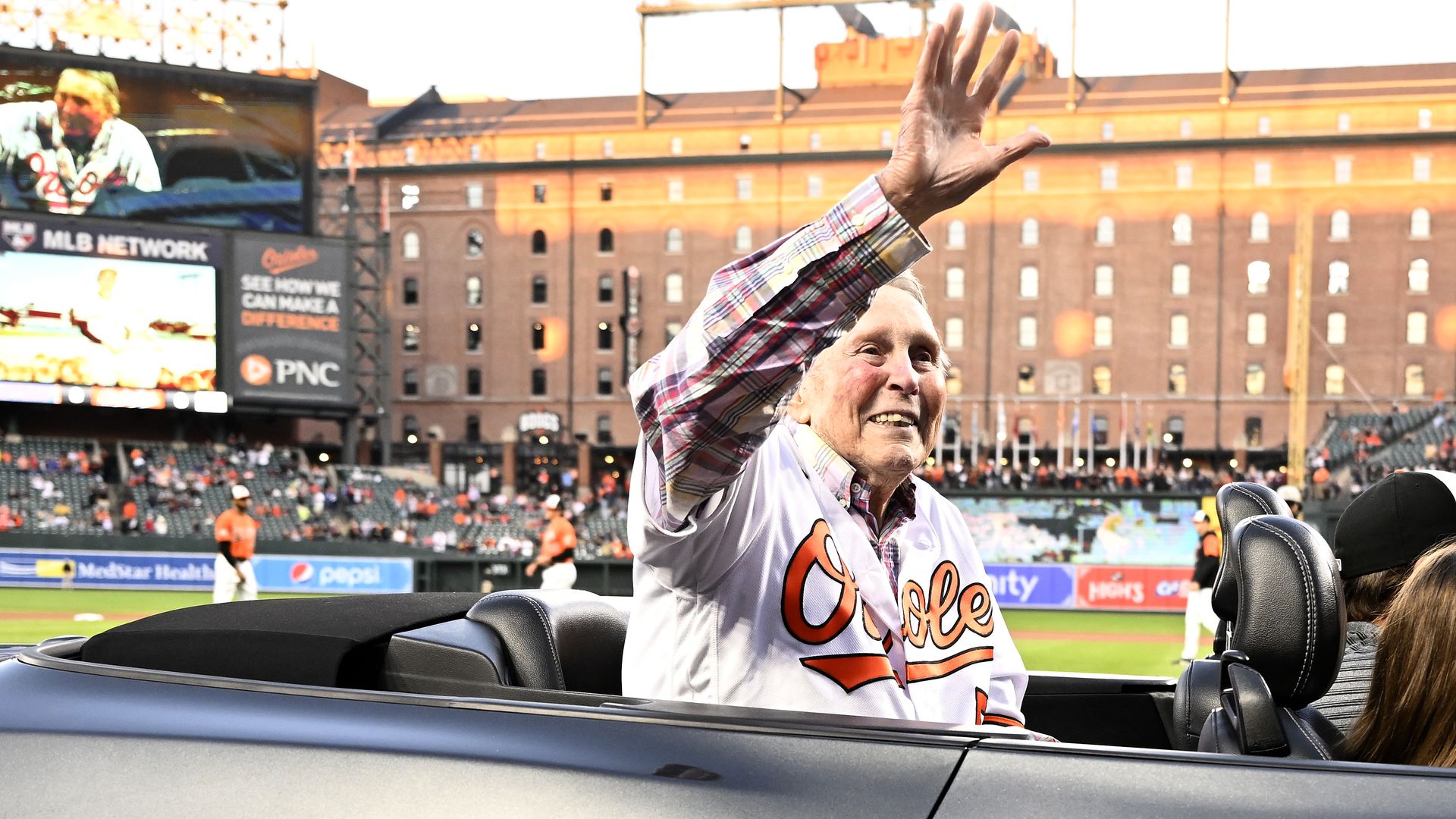 An aging Brooks Robinson rides in a convertible around Camden Yards and waves to the crowds
