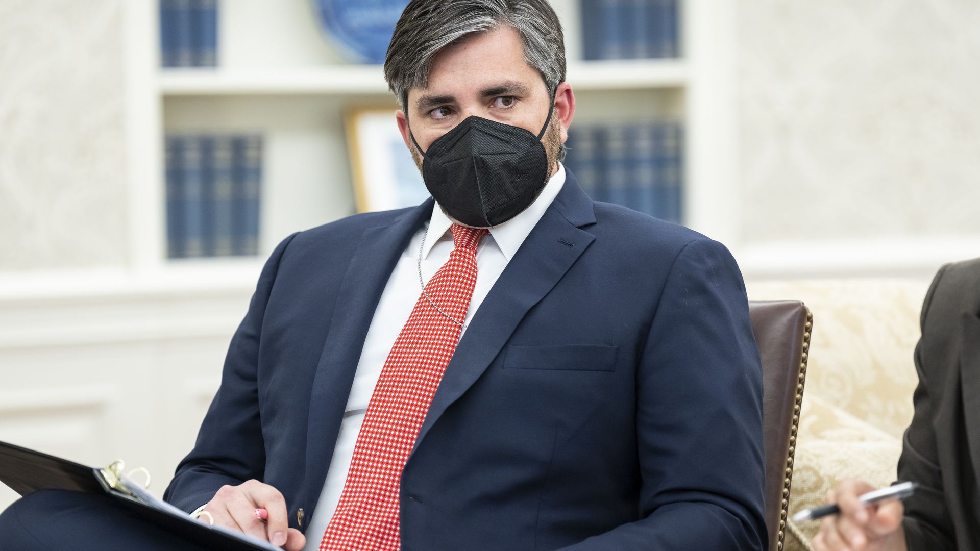 Photo of Zach Butterworth sitting in a chair wearing a mask. 