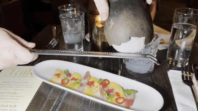 Salt is shaved across a narrow plate of tuna crudo.