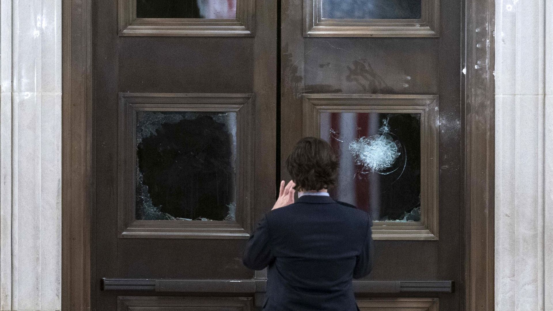 A person takes a photo of a smashed window at Congress.