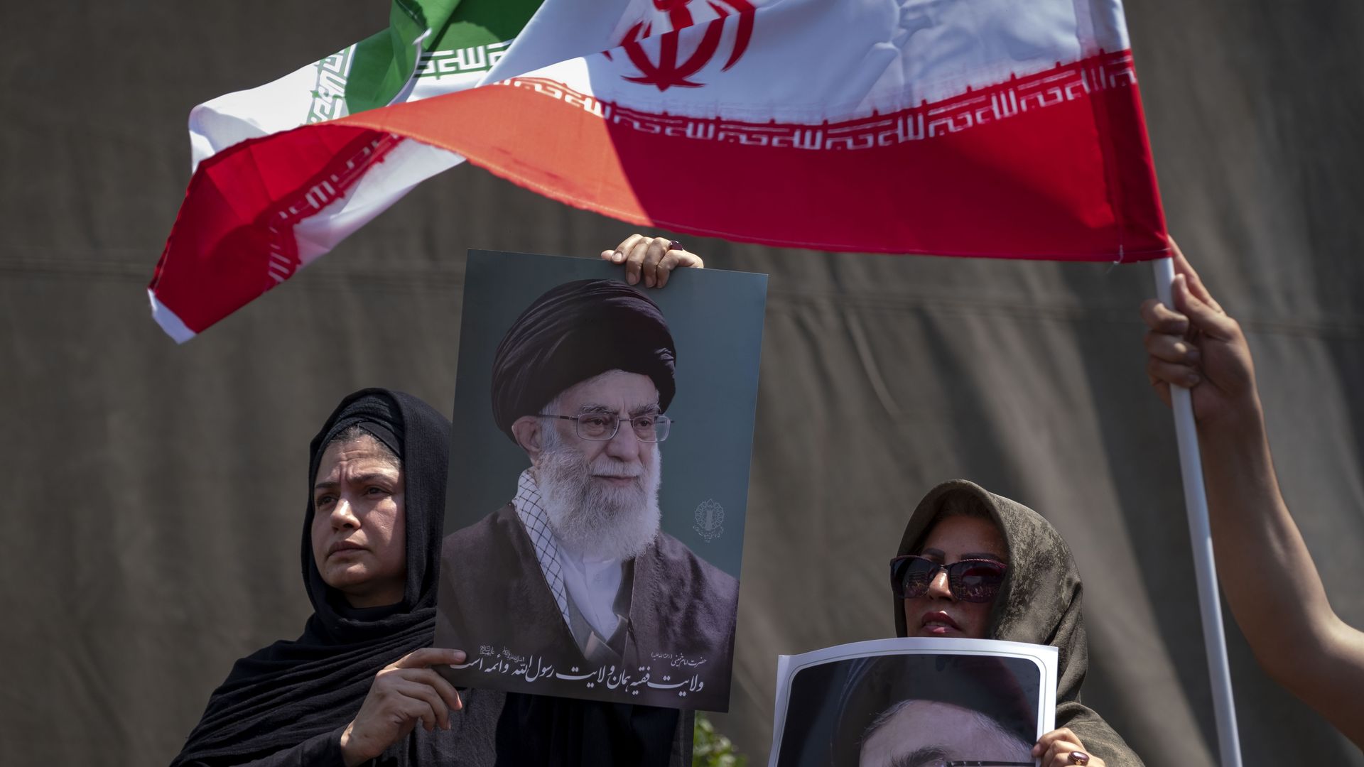 Iranian worshippers hold portraits of Iran's Supreme Leader, Ayatollah Ali Khamenei, and a country flag on June 13, 2025. (Photo by Morteza Nikoubazl/NurPhoto via Getty Images)