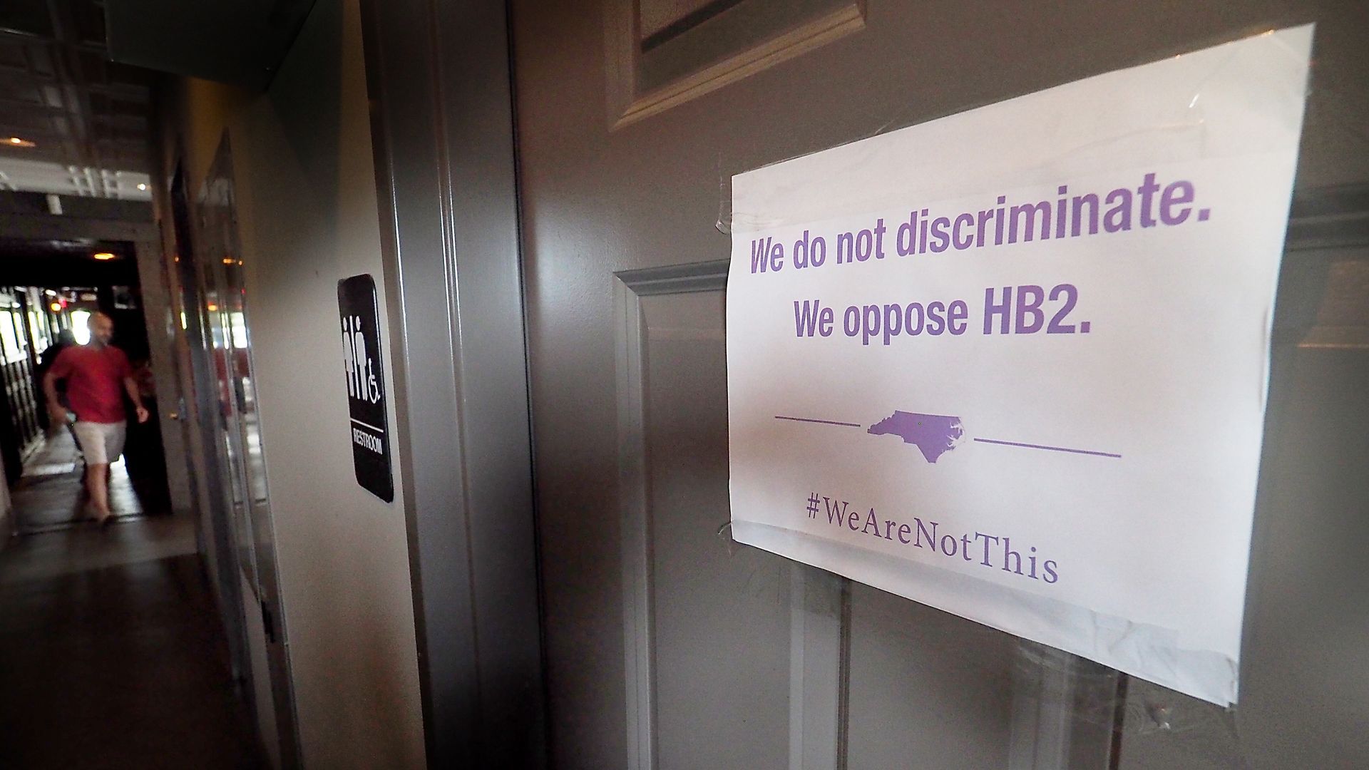 A unisex sign and the "We Are Not This" slogan are outside a bathroom at Bull McCabe's Irish Pub on May 10, 2016, in Durham. Photo: Sara D. Davis/Getty Images