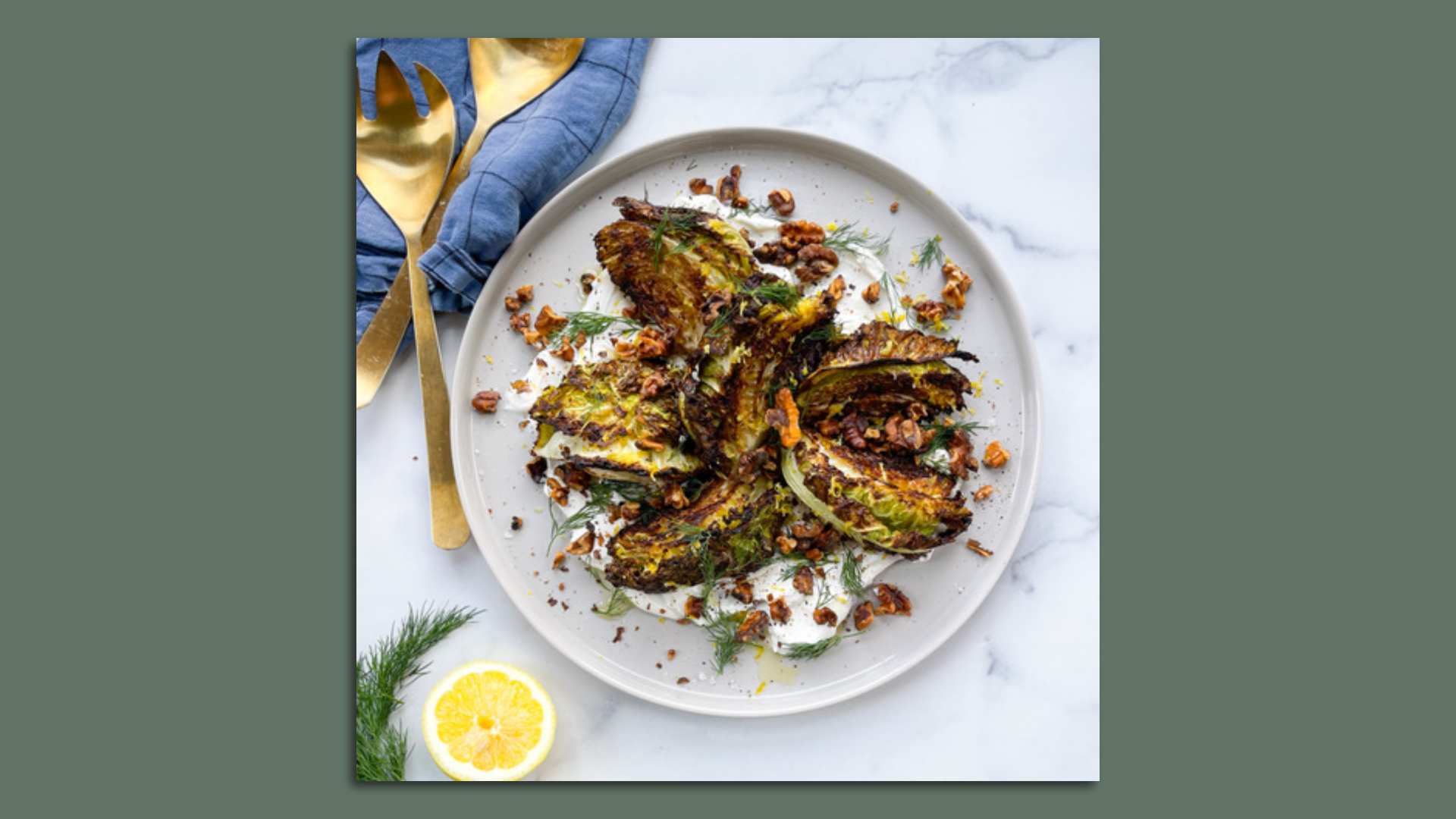 grilled cabbage wedges on a plate, surrounded by half a lemon and dill