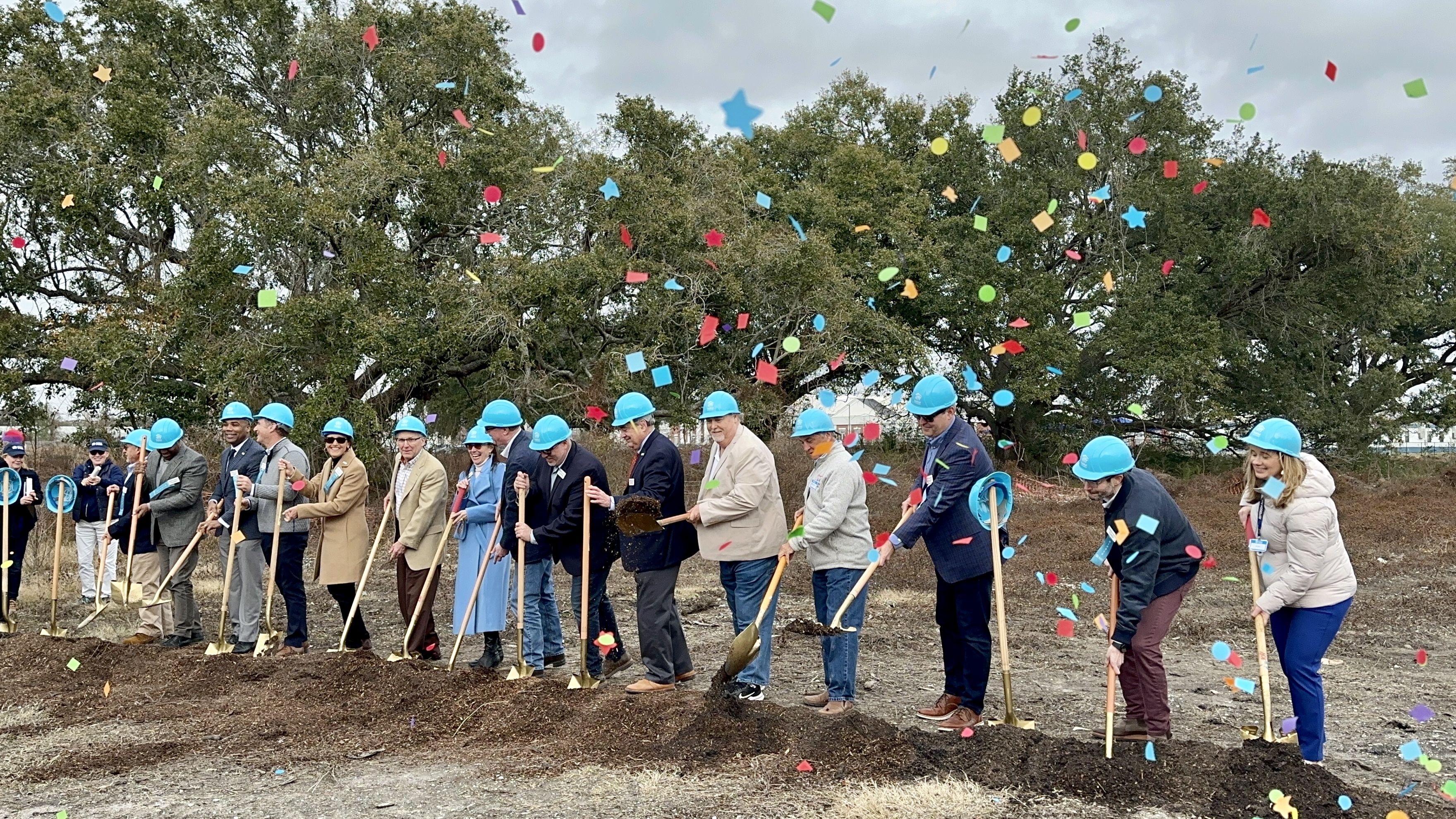 Photo shows people in blue construction hats with golden shovels.
