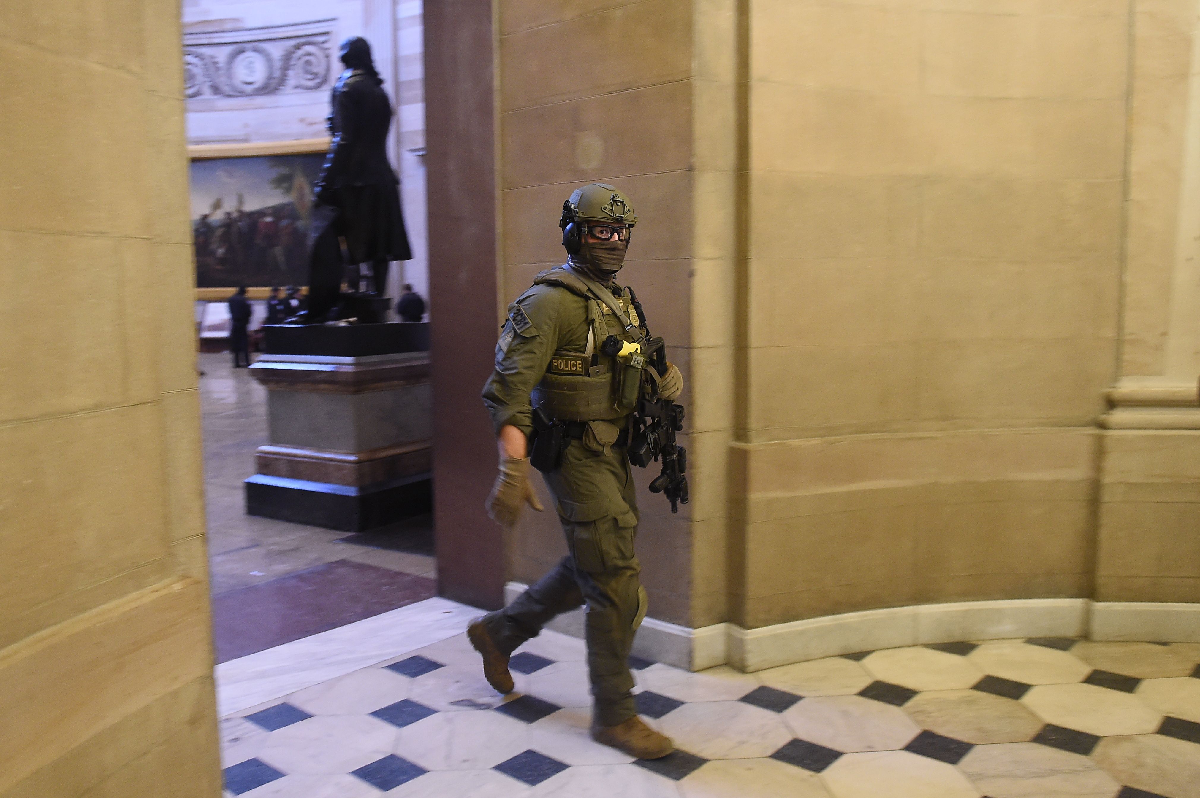A law enforcement officer in tactical gear is seen walking through the U.S. Capitol.