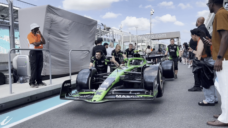 The Stake F1 Team Kick Sauber wheeling their race car down the pit lane.