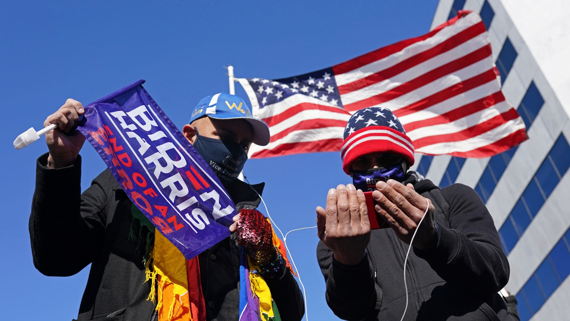 Supporters holds flags as they listen to U.S. President Joe Biden's inauguration speech on a smartphone on January 20, 2021 in Washington, DC. 