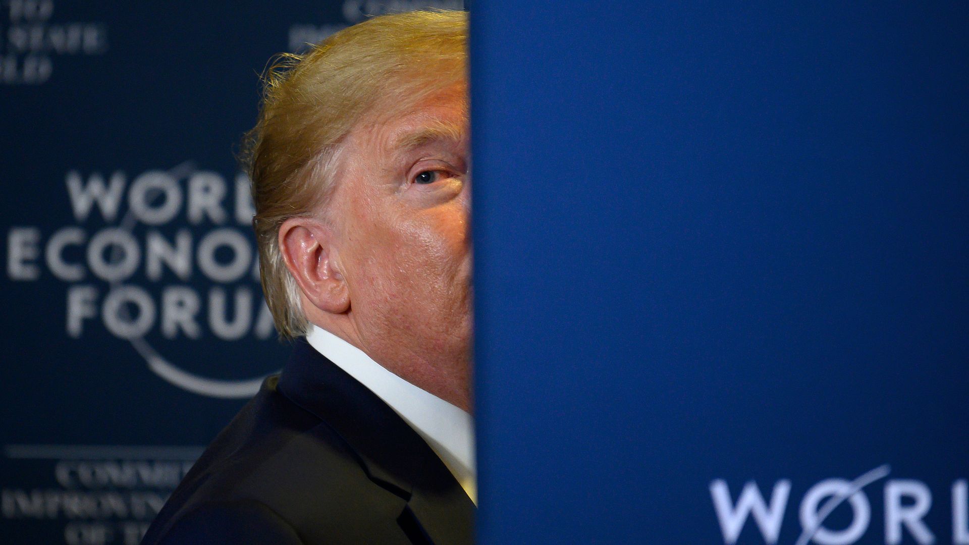 Donald Trump with half of his face hidden behind a wall as he exits