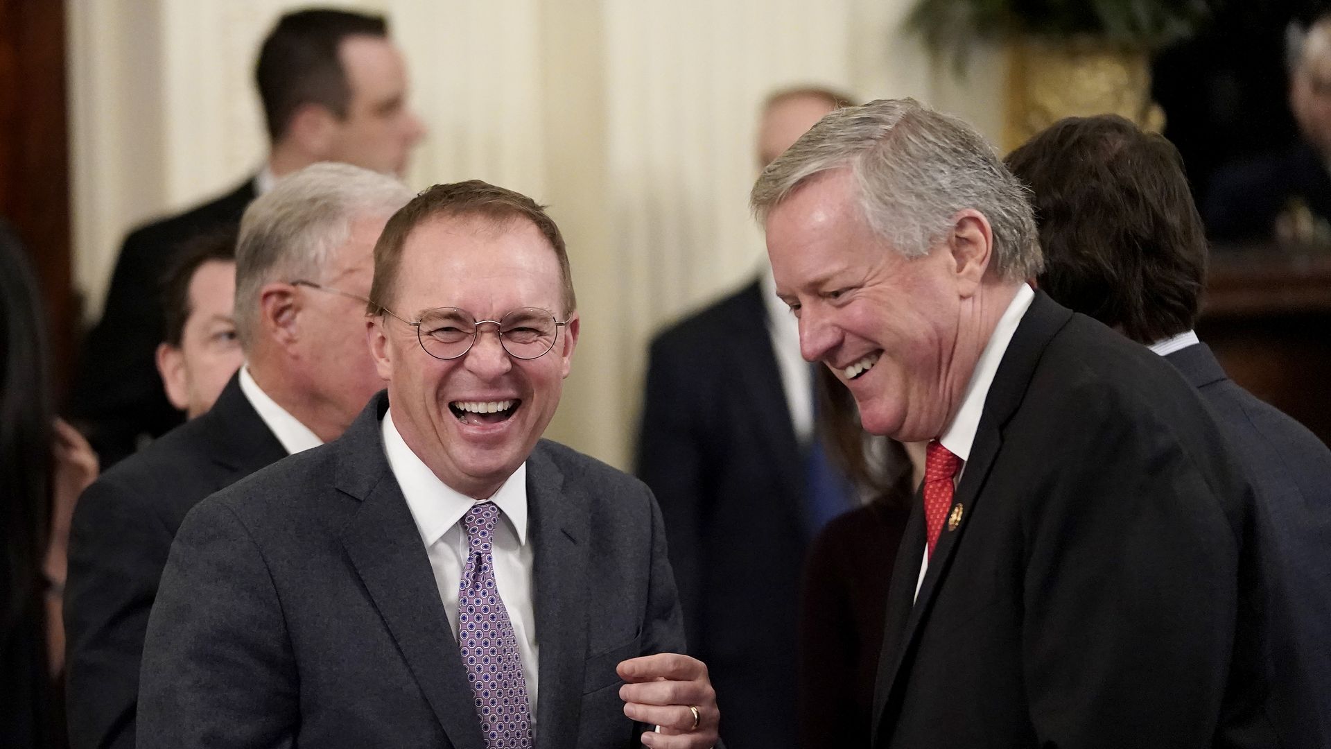 Mick Mulvaney and Mark Meadows stand next to one another while laughing