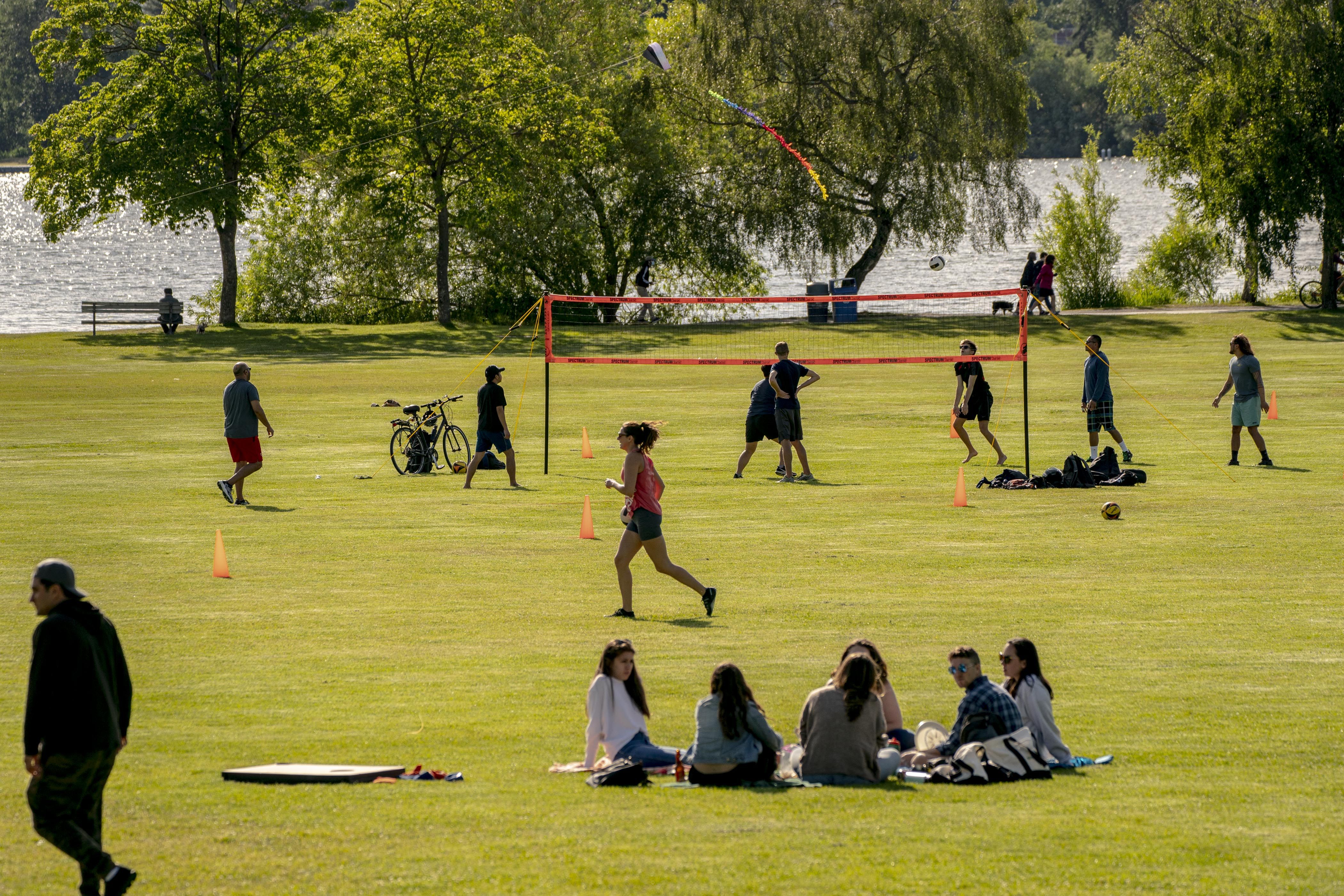 People play volleyball and sit in the grass next to Green Lake.