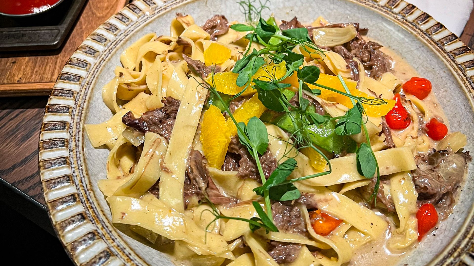 A plate of long, thick noodles with beef mixed in. 