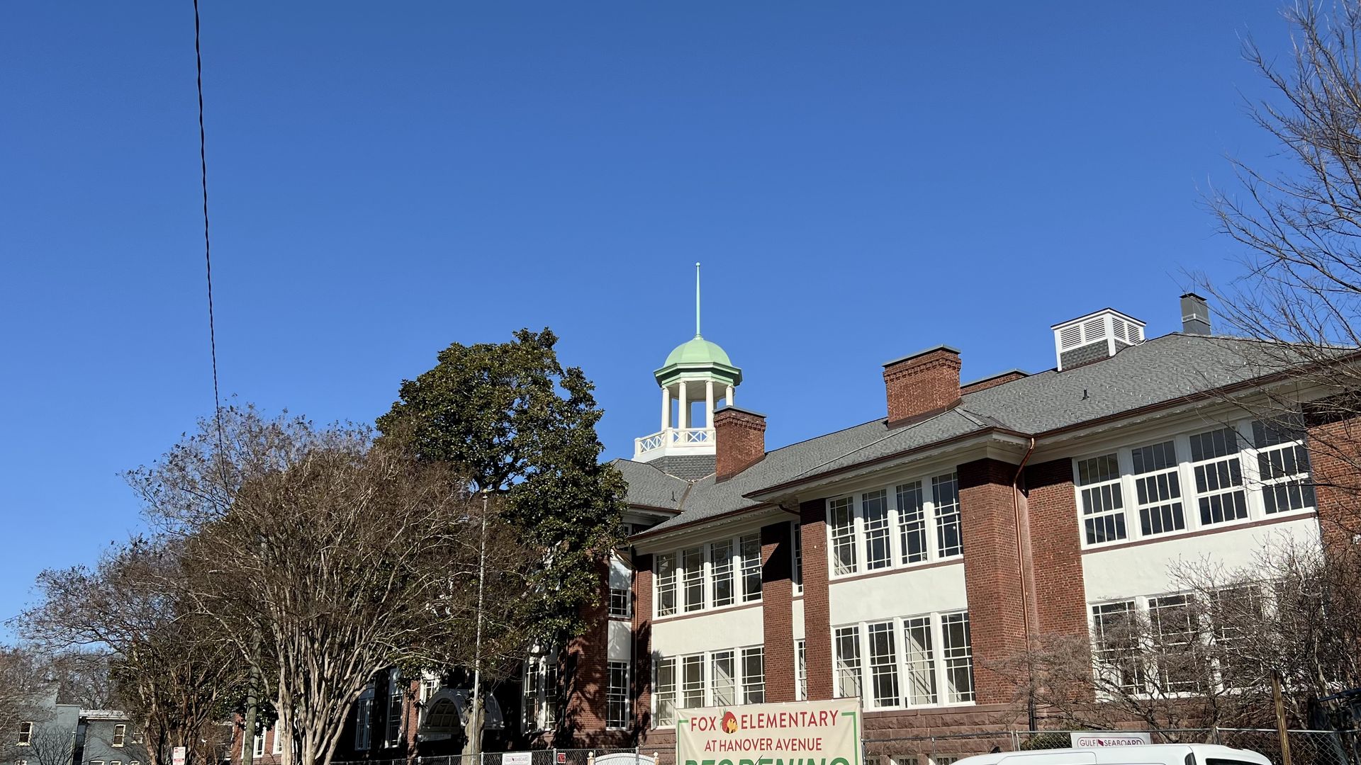 An elementary school surrounded by trees with a cupola on top