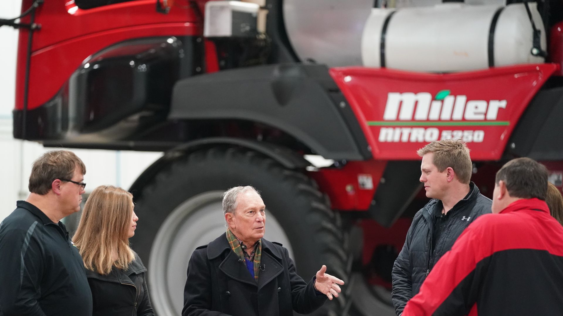 Michael Bloomberg talks to farmers in front of agricultural equipment
