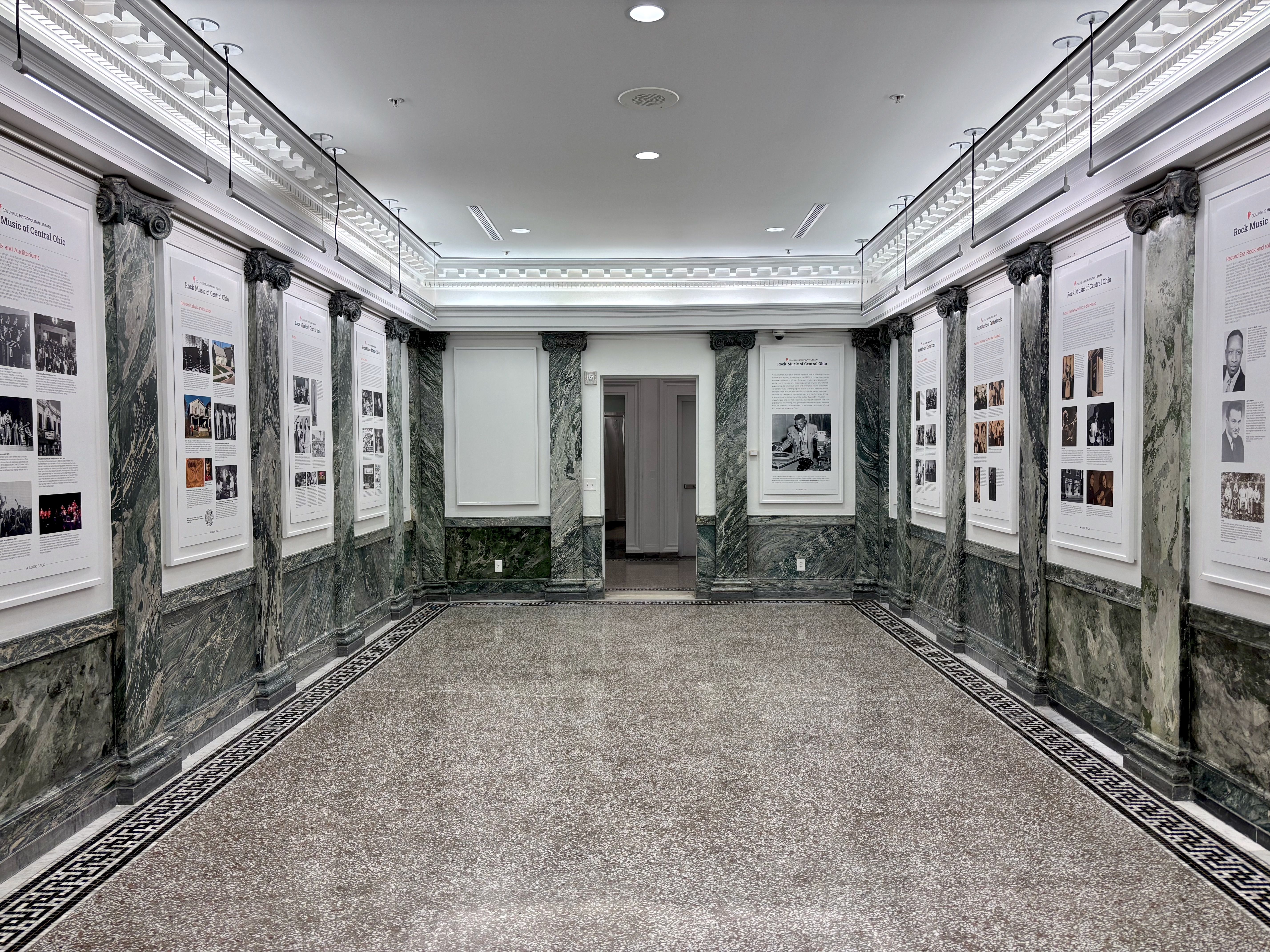 The library's History Gallery, a white and marble room, with historic photos and summaries on display like a museum, detailing Central Ohio rock music history