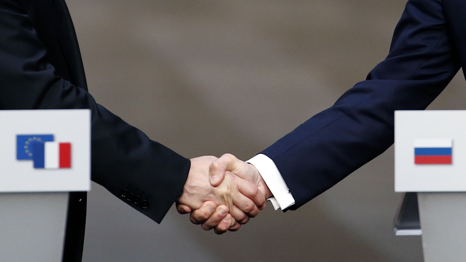 Putin's hand and Macron's hand during a handshake.