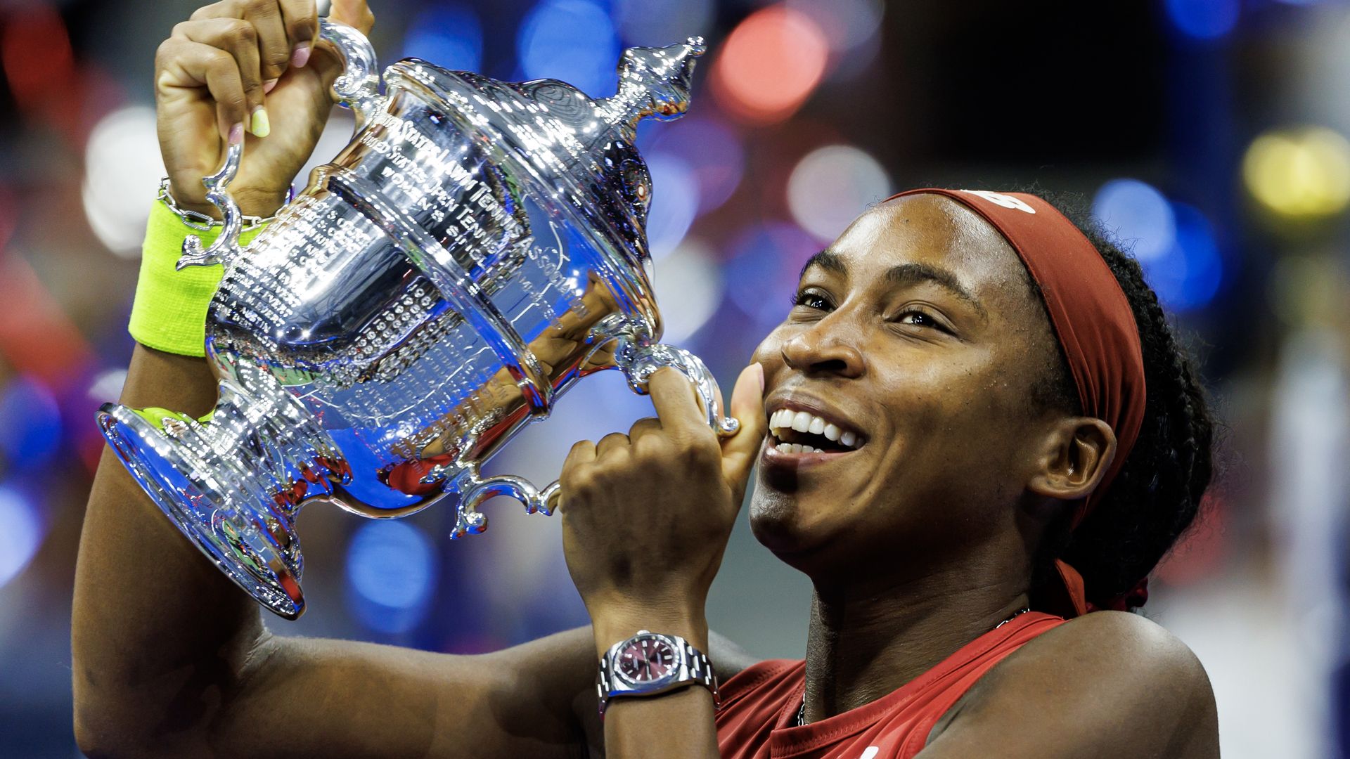 Tennis player Coco Gauff holds the U.S. Open trophy over her head and smiles