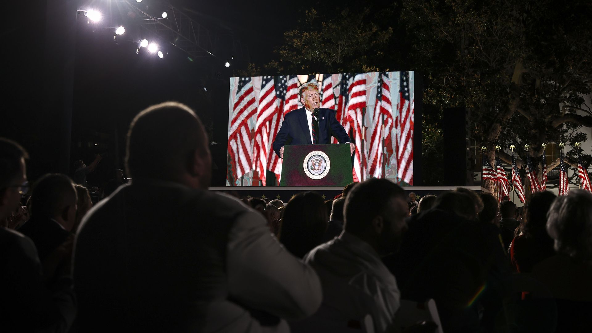 A video of Trump speaking plays to a crowd