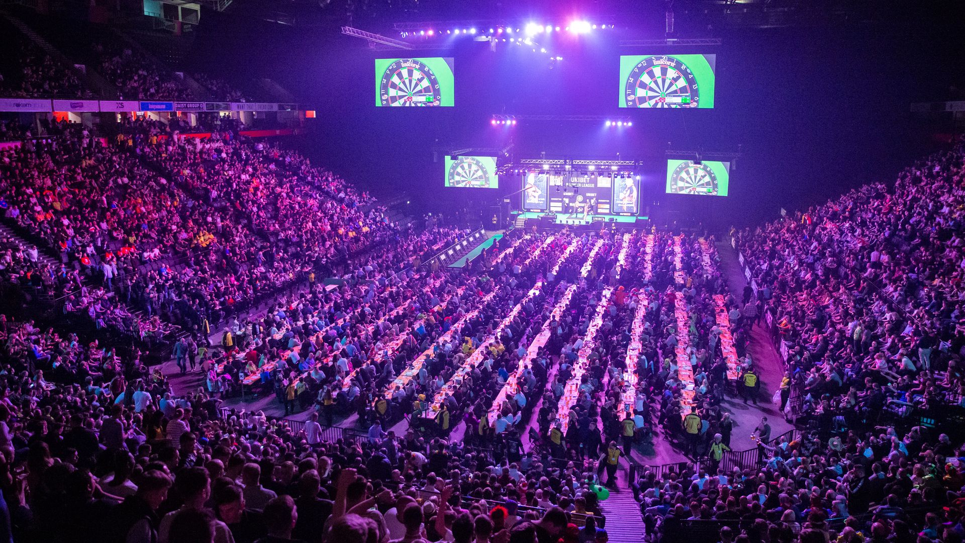 A crowd watching darts