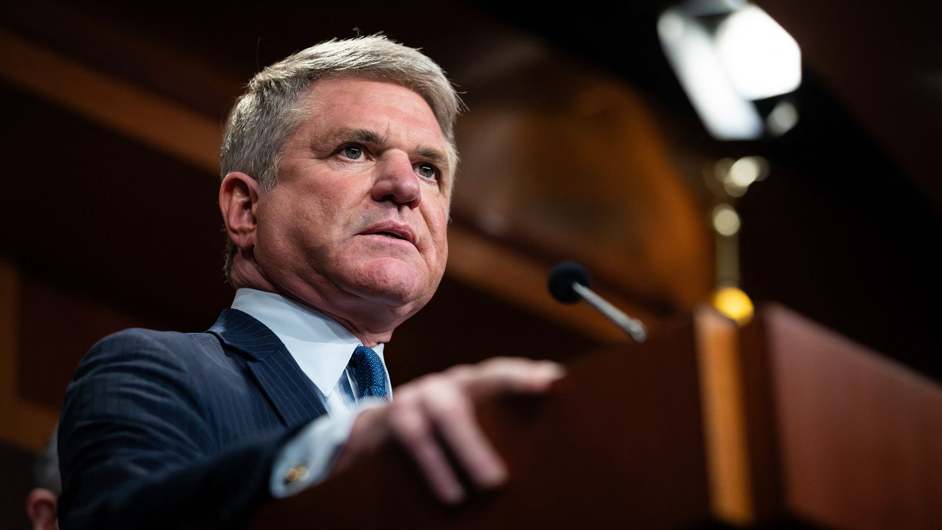 Rep. Michael McCaul, wearing a dark blue suit, light blue shirt and blue tie, grasping a podium.