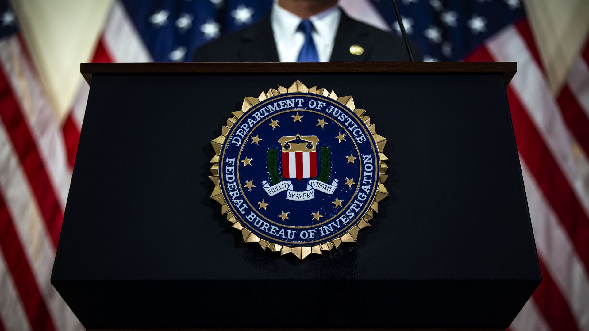 Photo of an unidentifiable person speaking from a podium that has the FBI seal