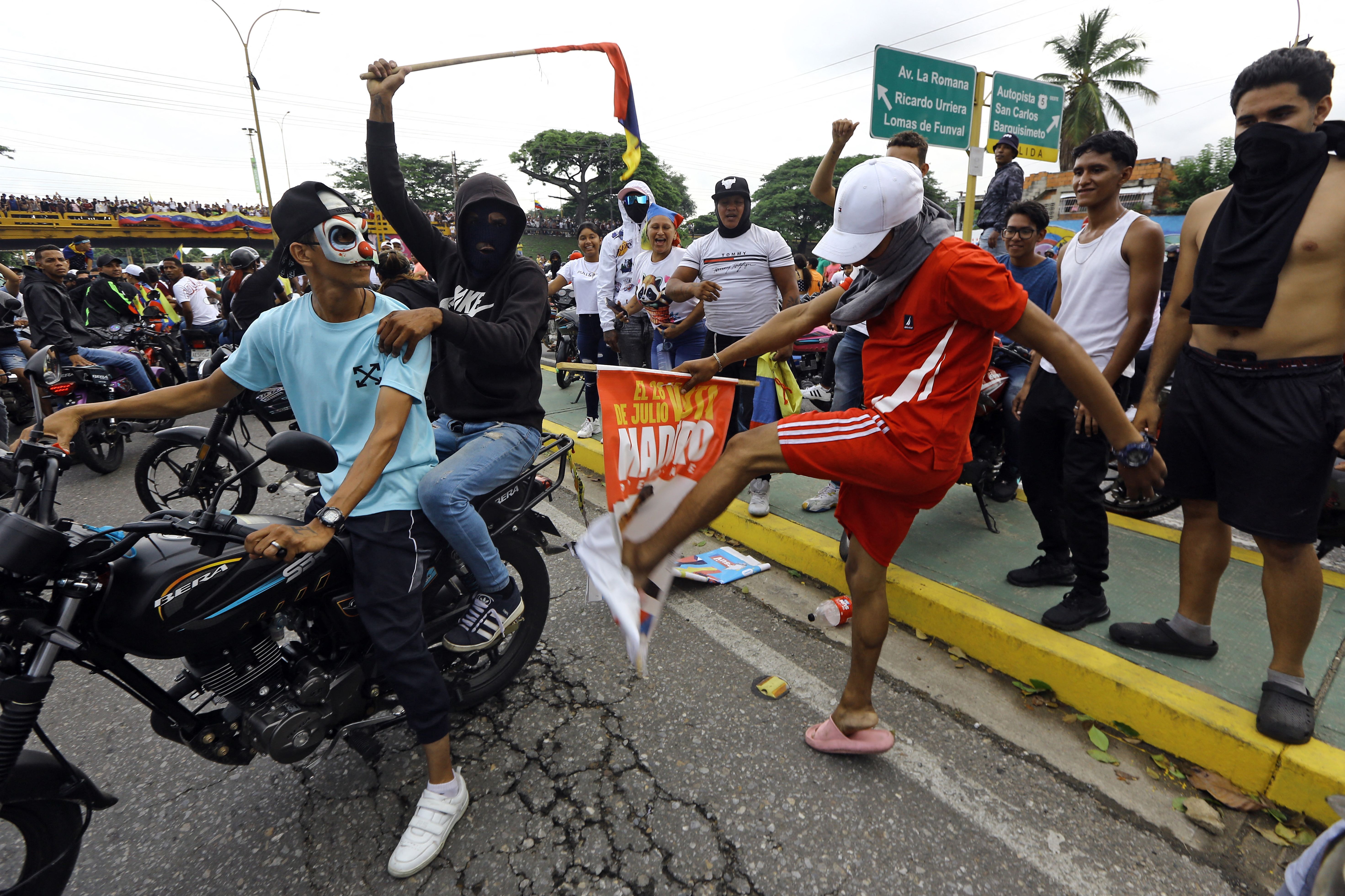 A demonstrator kicks a campaign banner of Venezuelan President Nicolas Maduro during a protest in Valencia, Carabobo state, Venezuela on July 29, 2024.