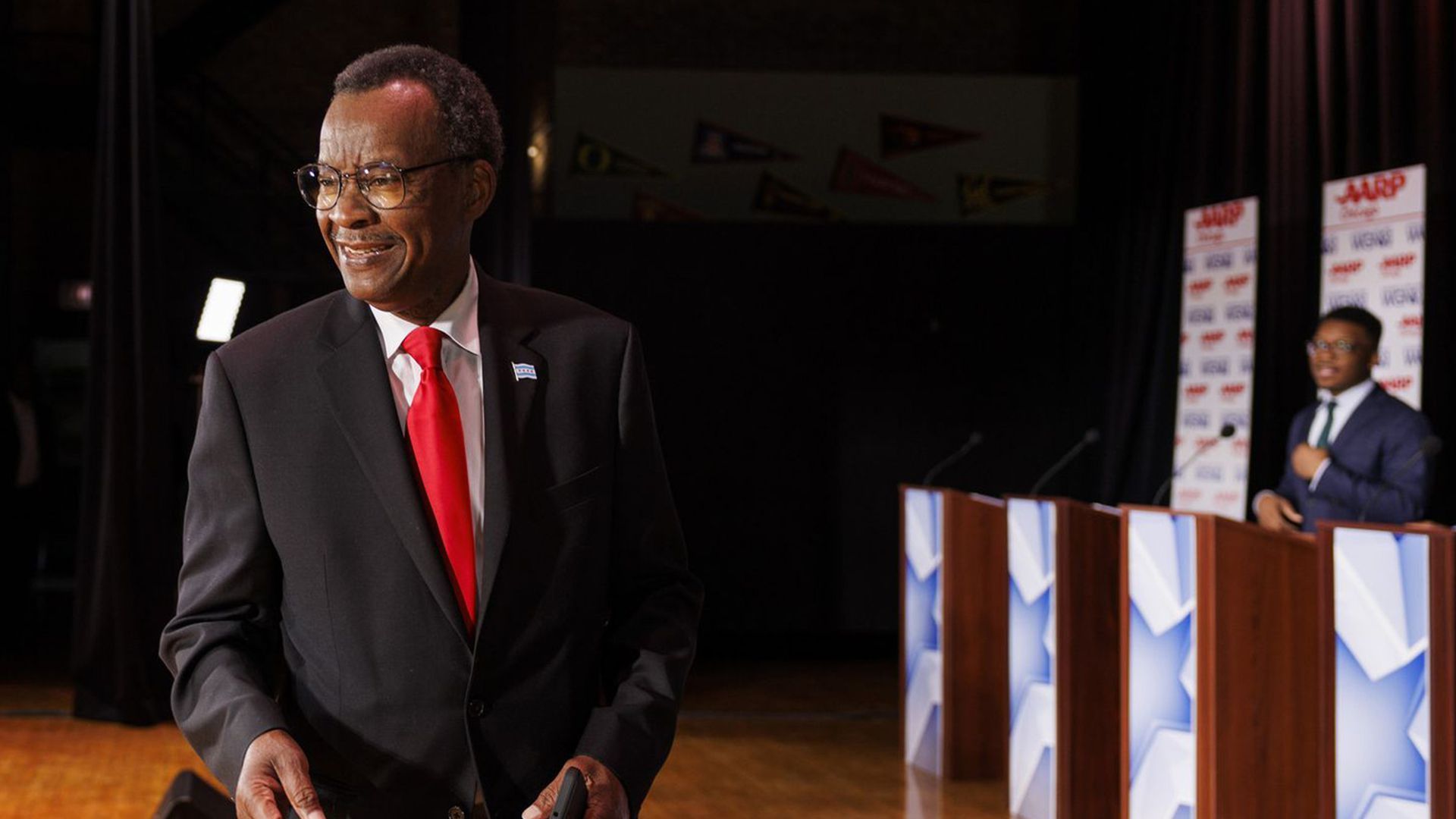 Willie Wilson smiles while wearing a black suit and a red tie on a stage.