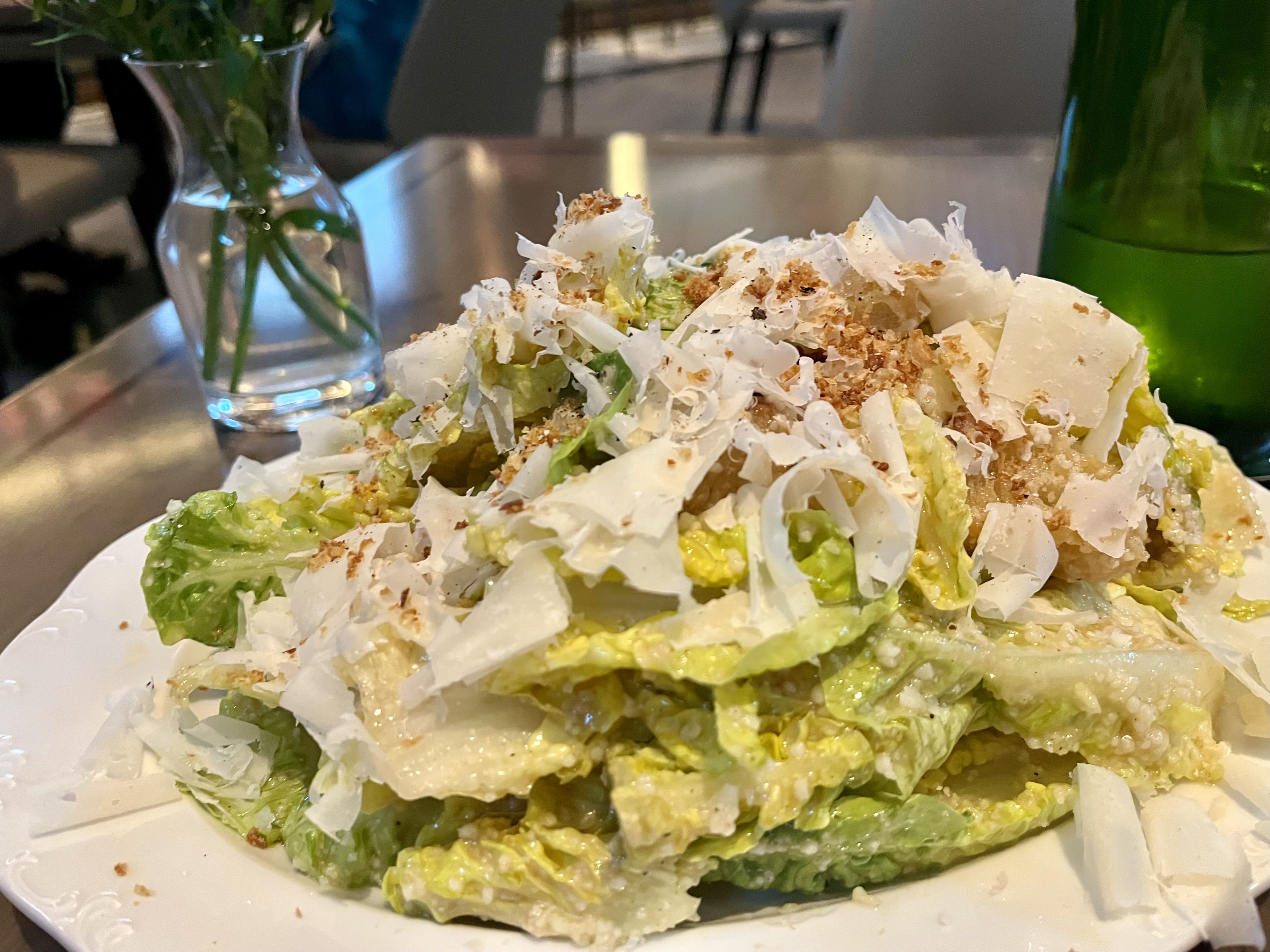 A close-up shot of a Caesar salad topped with breadcrumbs and shaved parmesan.