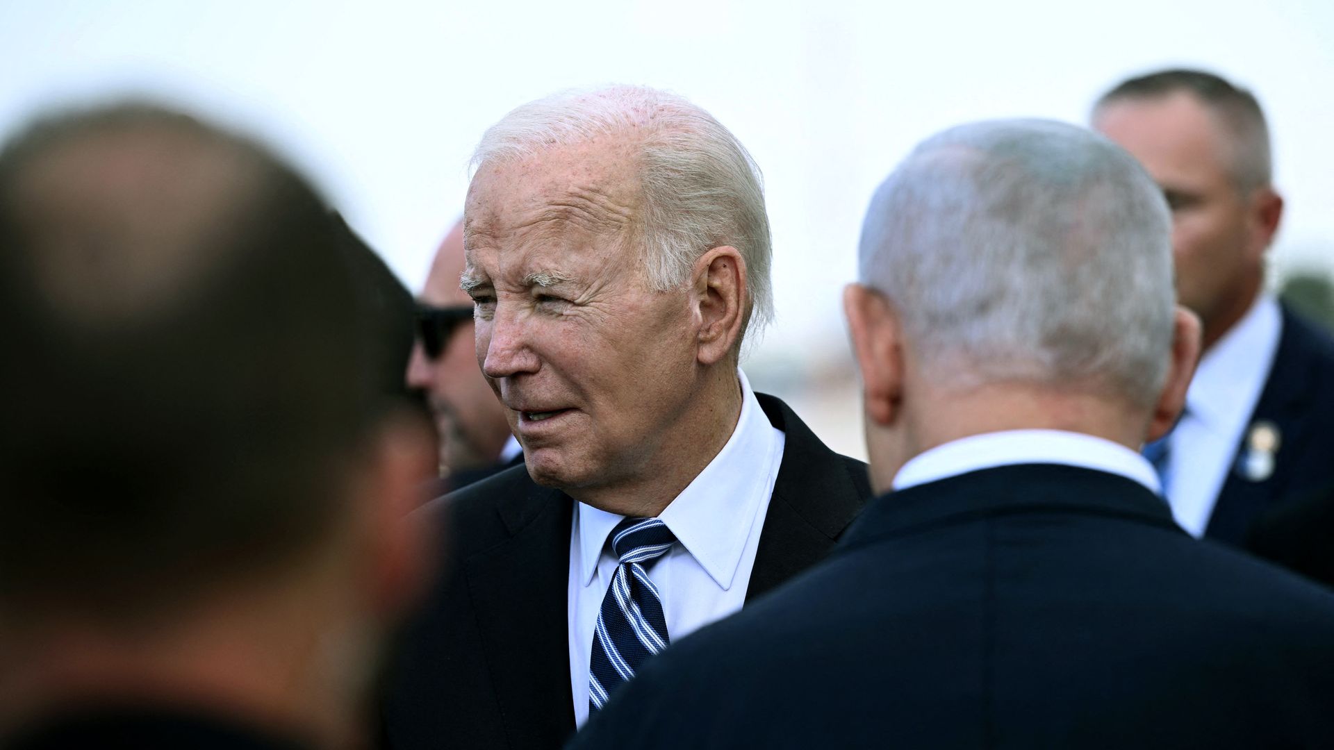 Biden, surrounded by other men, looks off camera