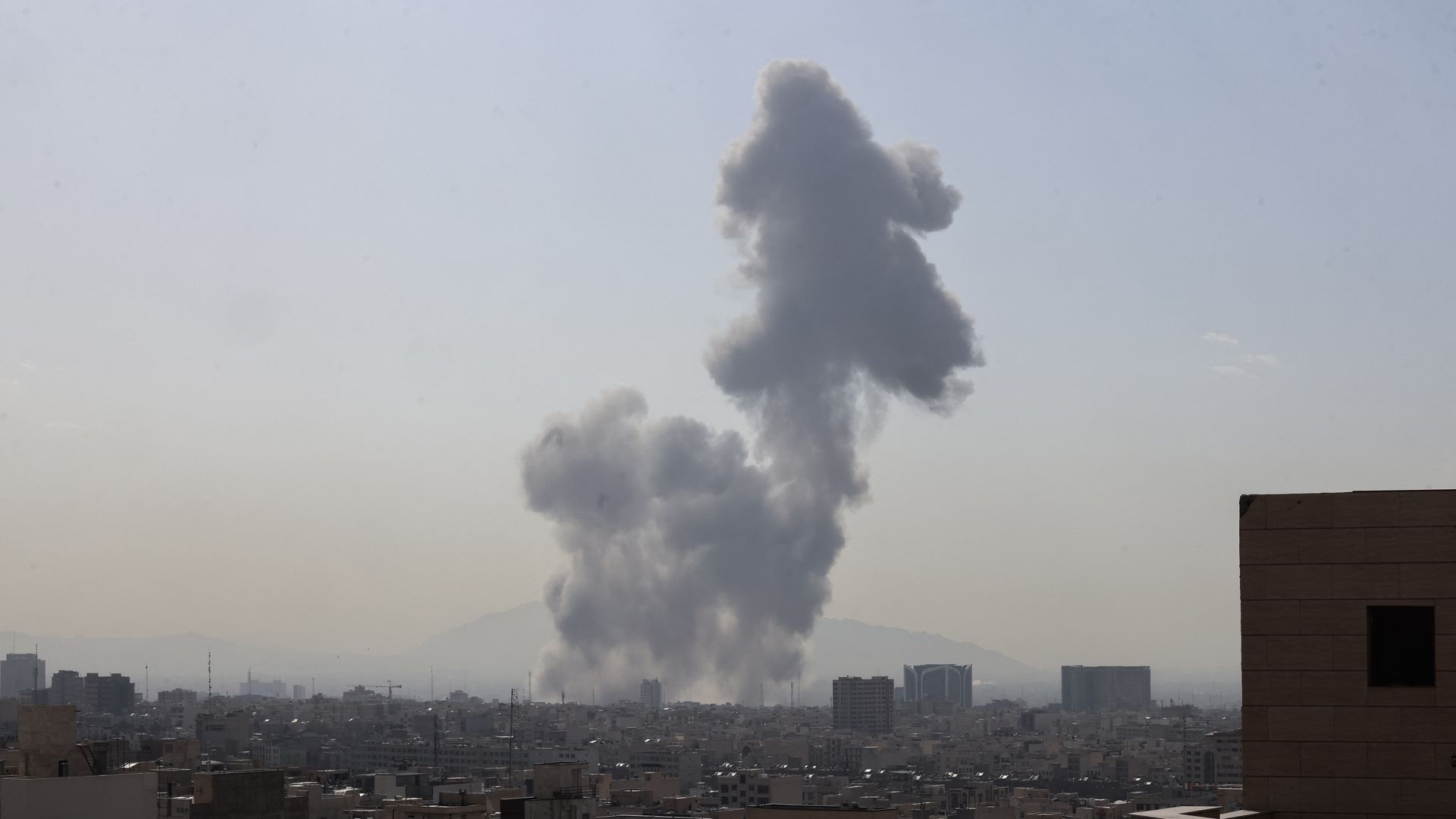 Thick plumes of smoke billow into the sky above buildings in Tehran after reported explosions.