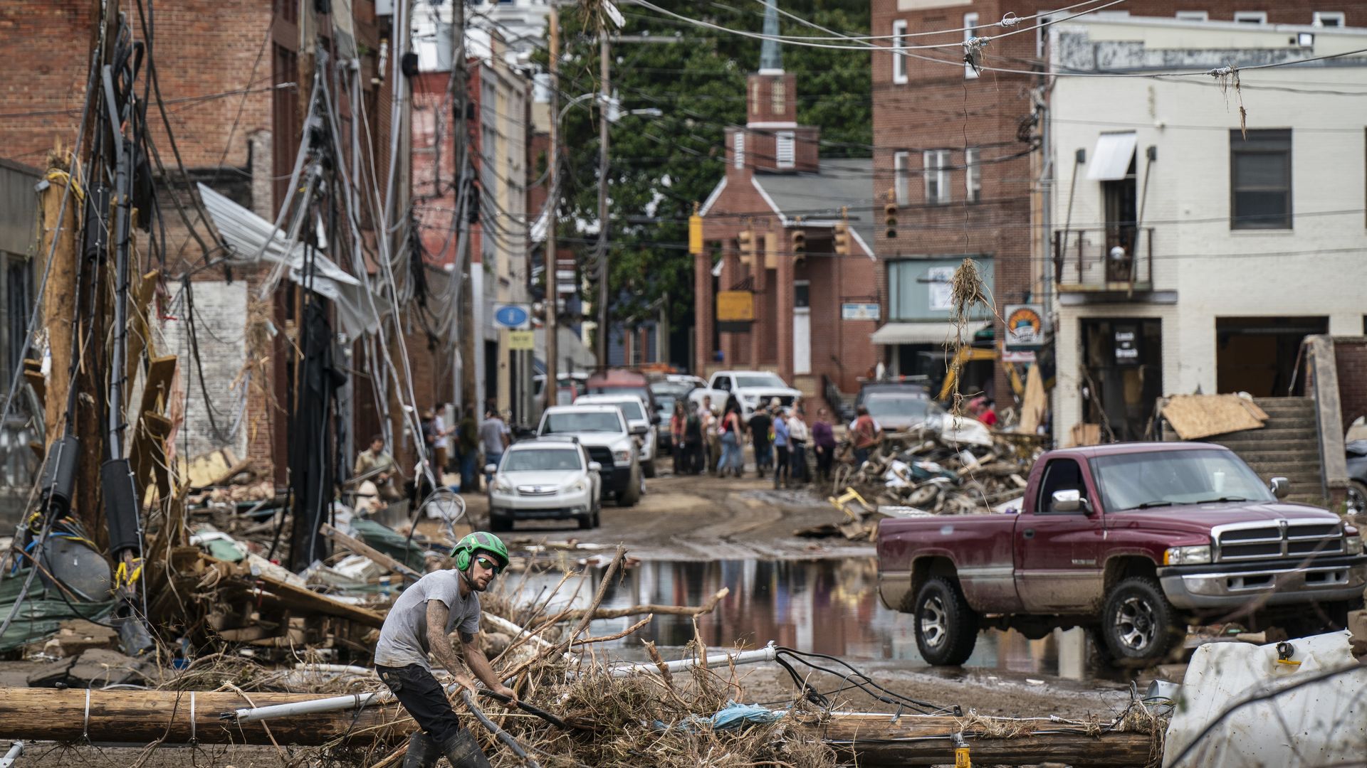 Workers, community members and business owners clean up debris on a street in the aftermath of Hurricane Helene in North Carolina.