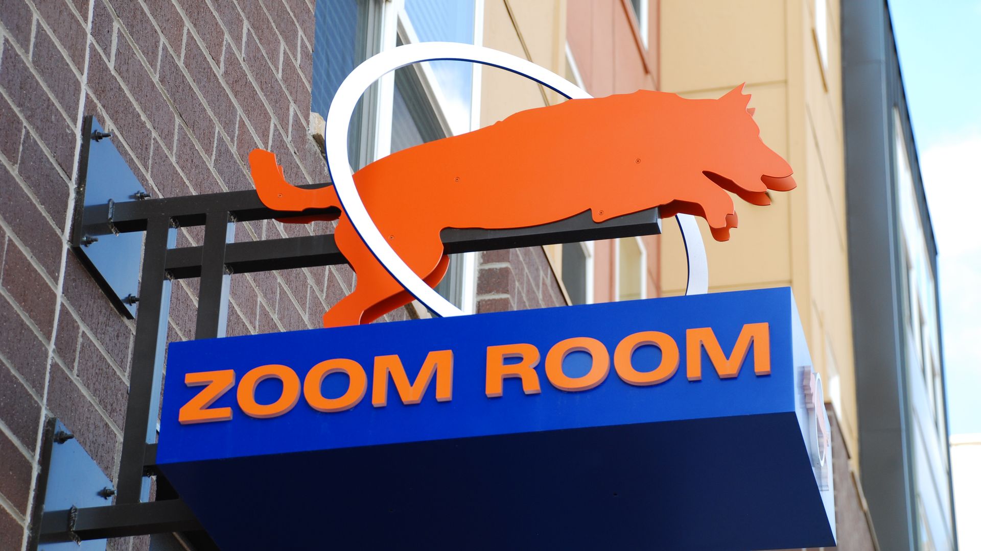 A store sign for Zoom Room hangs off the side of a building.