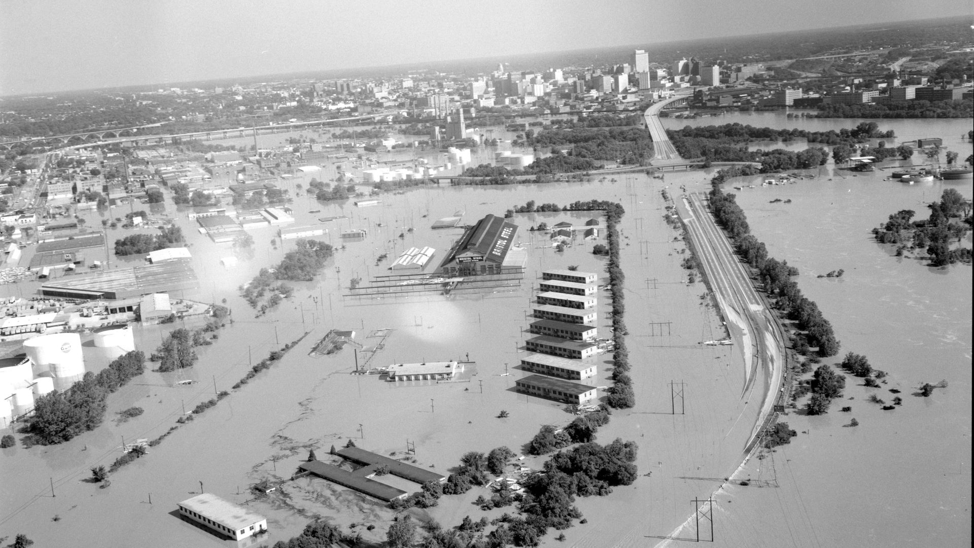 A flooded James River is shown swallowing a river with the city in the background